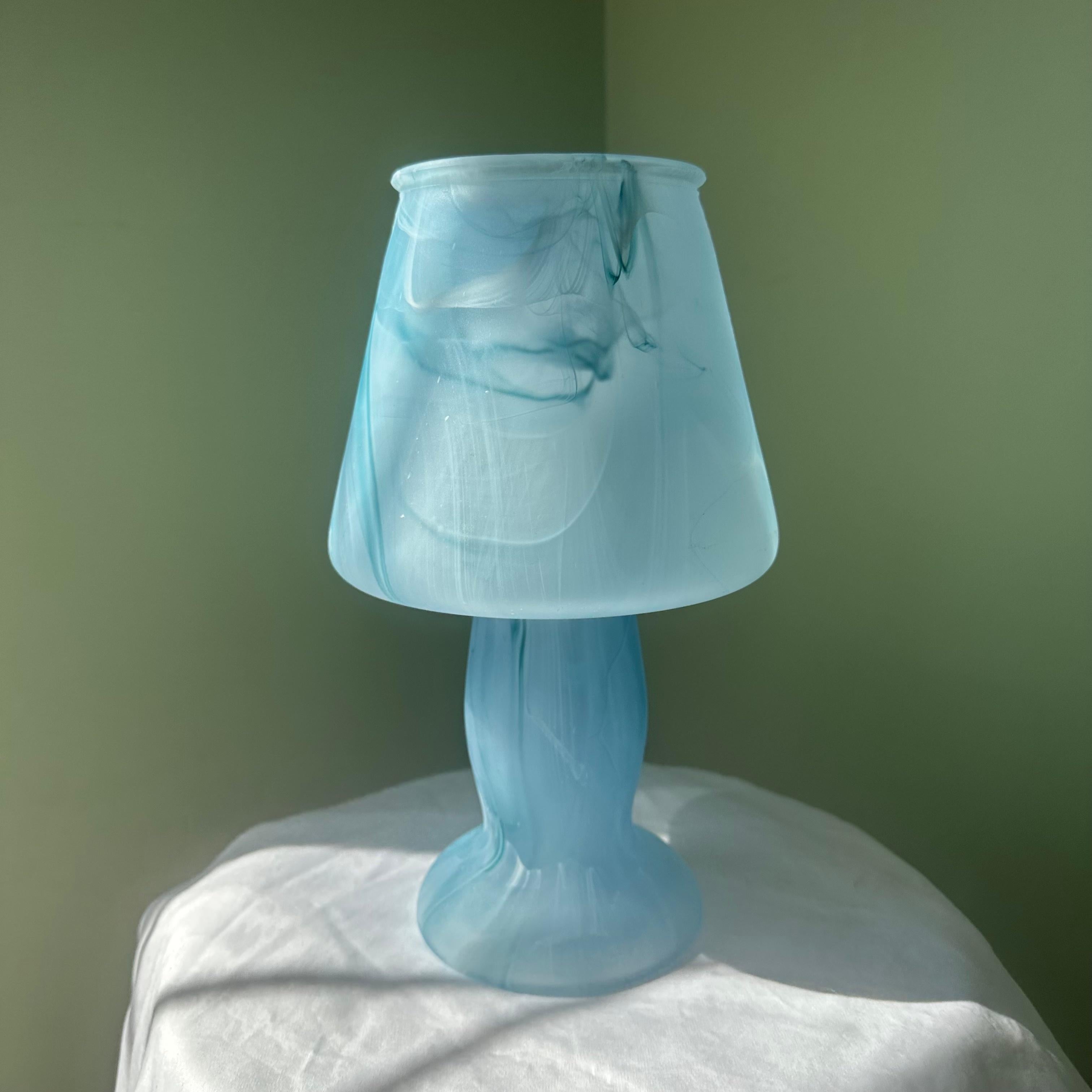 Blue glass mushroom table lamp or desk lamp. Swirling in a tie-dye like pattern, shades of blue mix with touches of white. Molded in a single, solid piece of glass, this lamp is open at the top. An absolutely gorgeous piece of colored glass. Uses