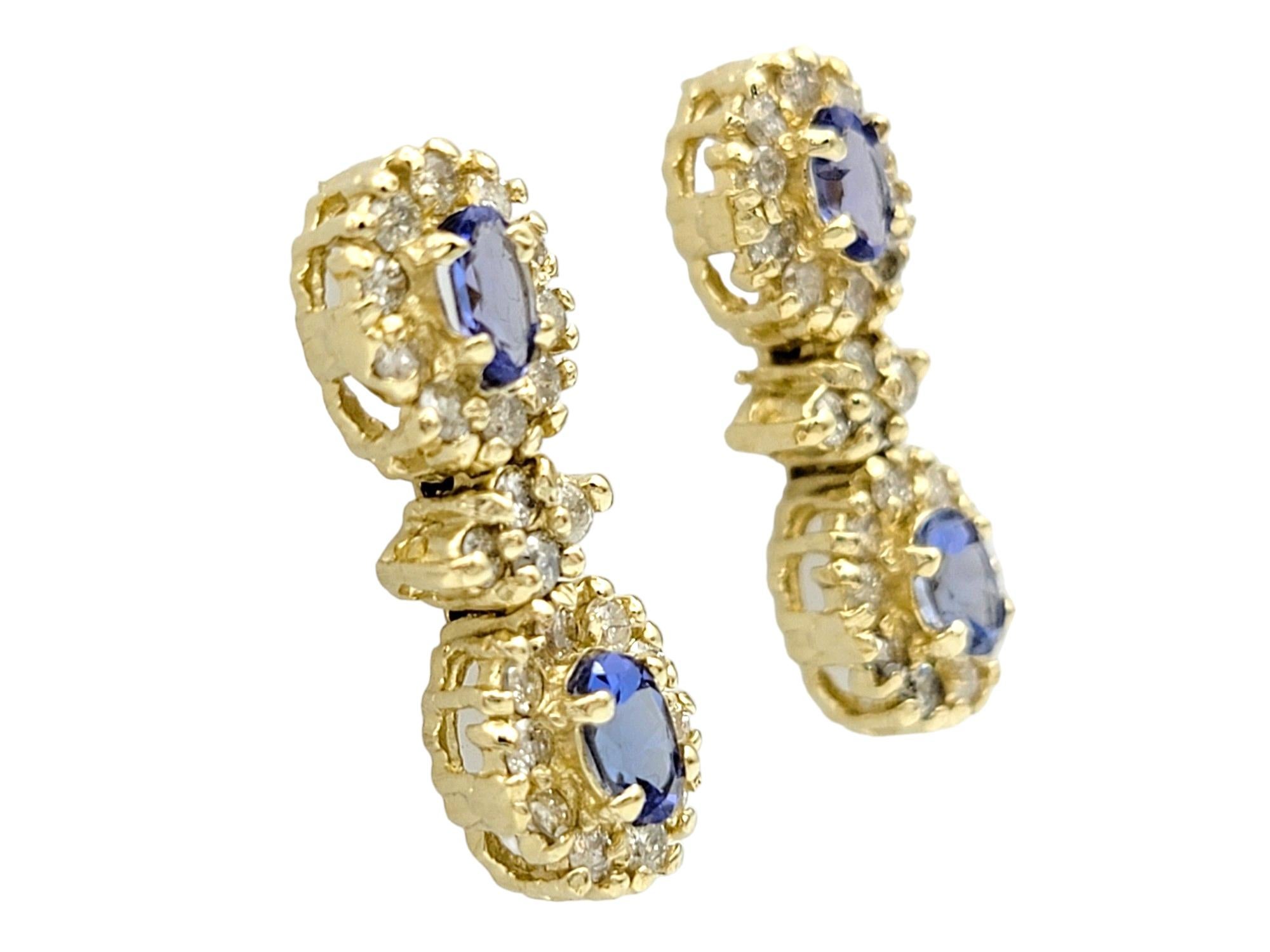 Contemporary Blue Tanzanite and Diamond Halo Dangle Earrings Set in 14 Karat Yellow Gold For Sale
