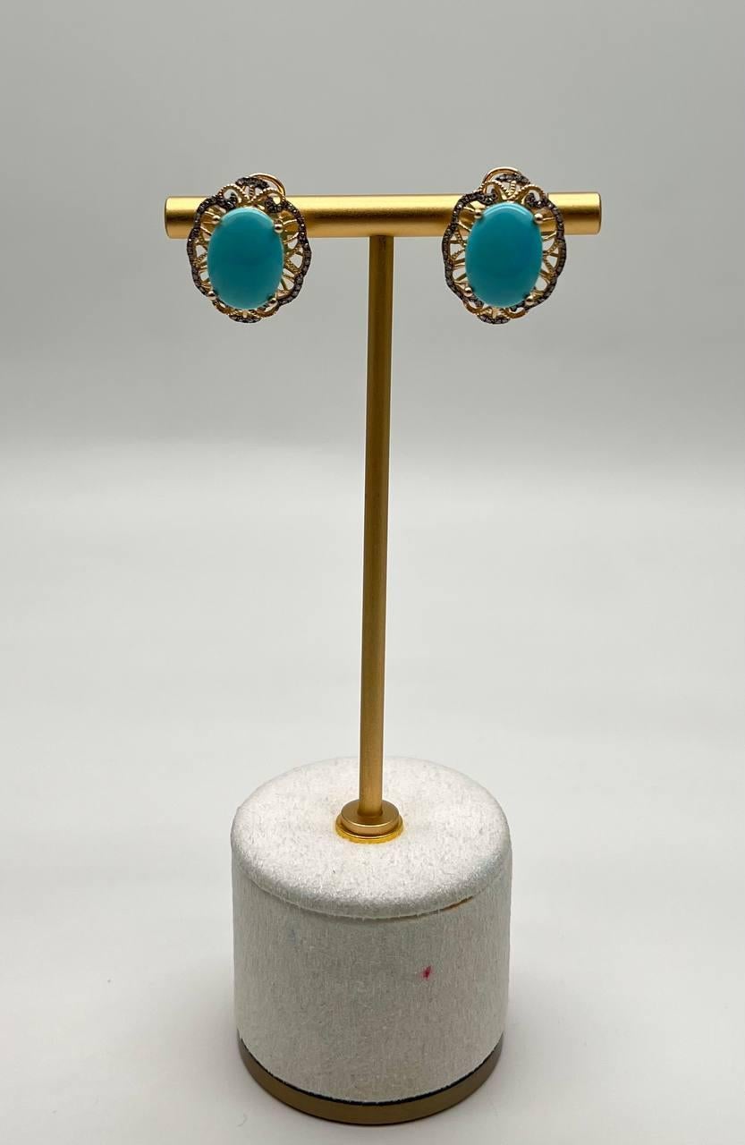 These exquisite earrings feature a vibrant turquoise oval stone set in a delicate gold frame. The intricate design includes a halo of small, sparkling diamonds surrounding the central stone. Crafted with precision, these earrings are a testament to