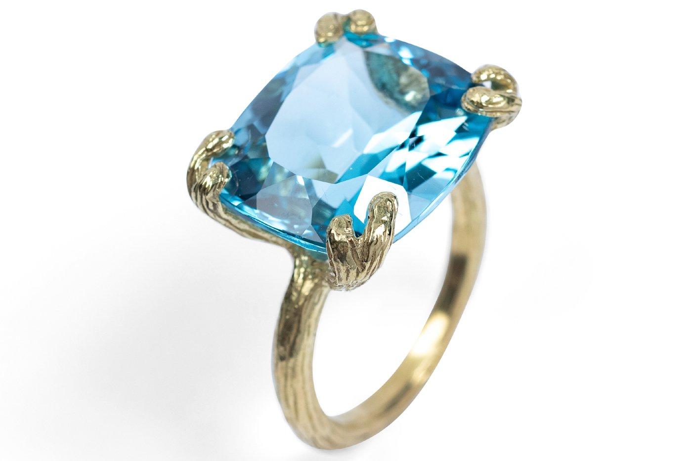 Faceted Swiss blue topaz recalls the brightest summer skies, sparkling atop Gabrielle's 18k textured claw setting. 16x18x10mm Swiss blue topaz.

GSR55BlTpz — Blue topaz 16x18x10mm faceted rectangle18k textured claw ring
