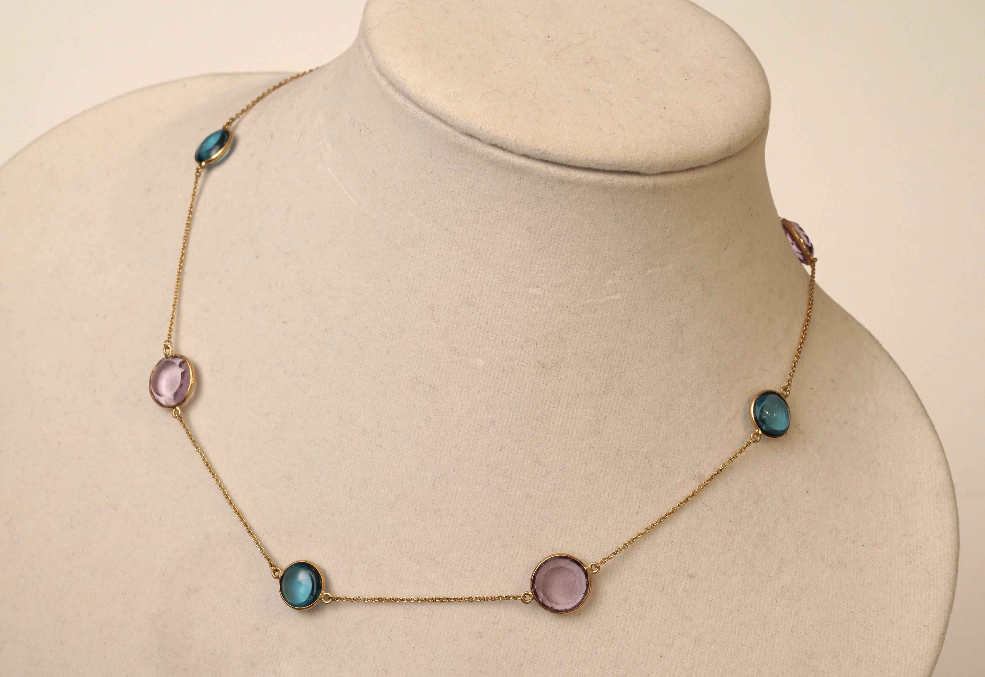Alternating blue topaz and amethyst stones bordered in 18K gold on a delicate 18K gold chain.  The blue topaz are cabochons and the amethyst are faceted, and stones are open on both sides.  The diameter of the amethyst are 1/2 inch and the blue