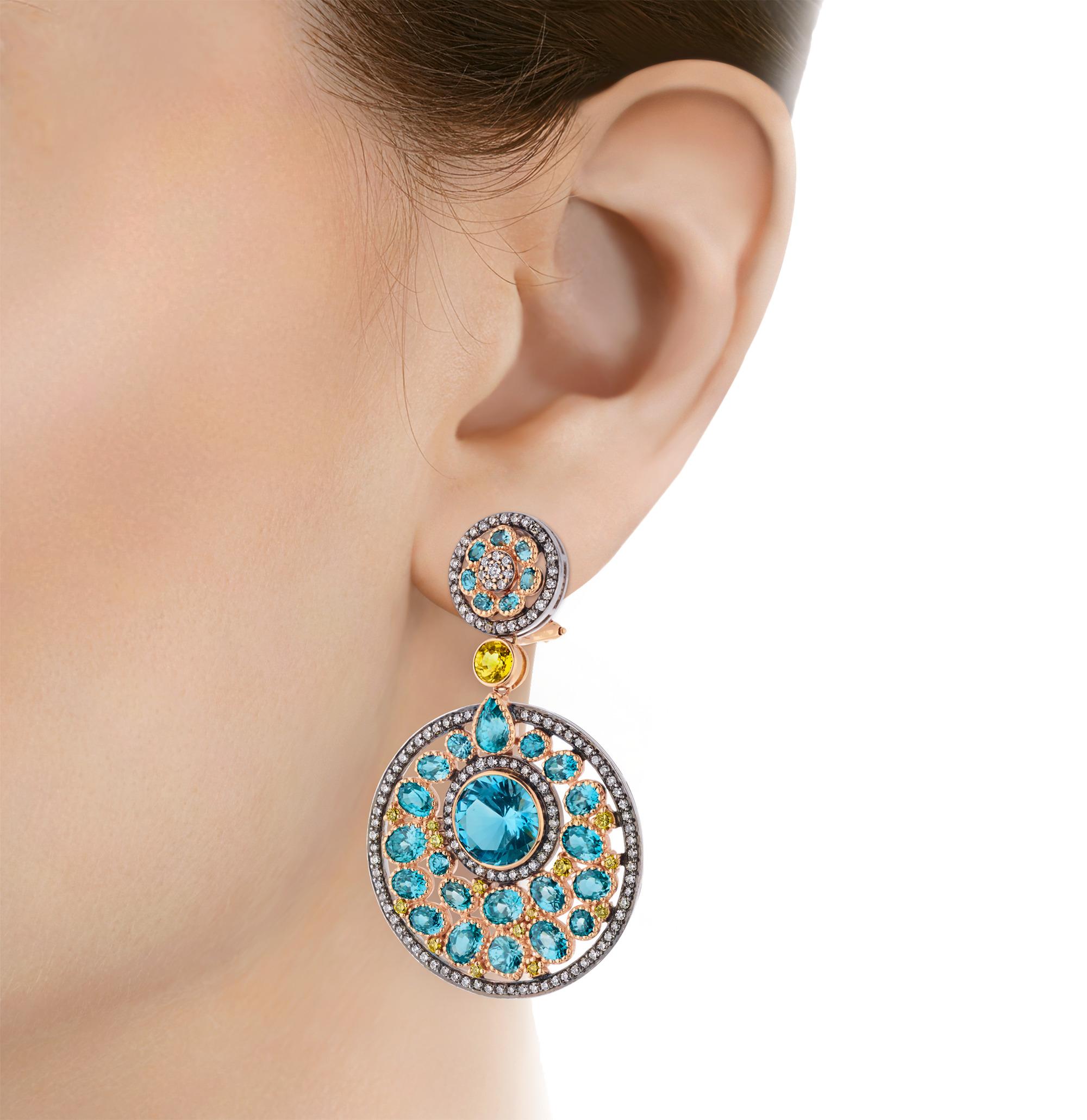 Questi magnifici orecchini a lobo presentano una costellazione mozzafiato di gemme blu in medaglioni circolari stratificati. Il design drammatico presenta più livelli di topazio blu brillante per un totale di 10,75 carati e zircone blu per un totale