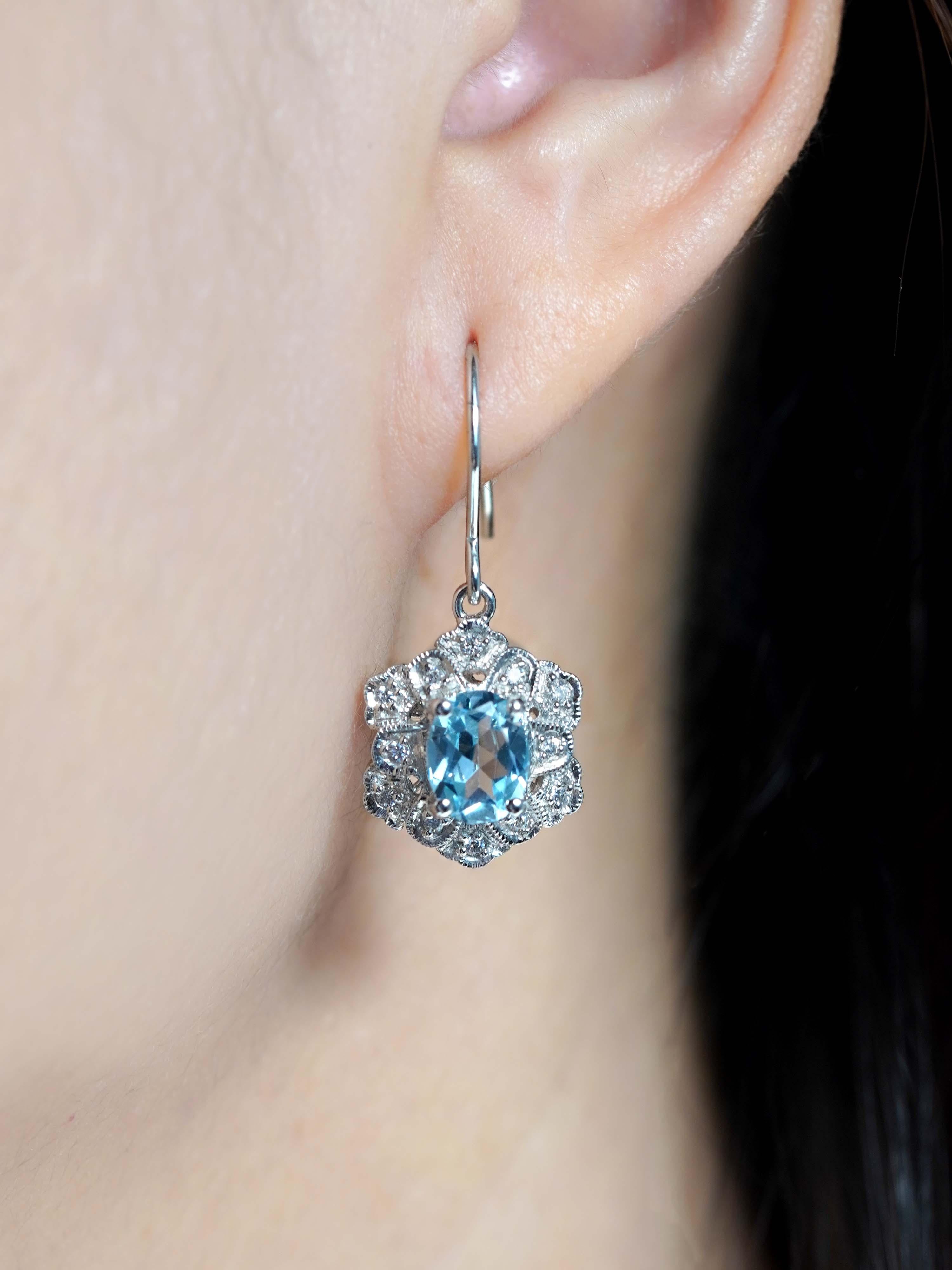 Ispirati al glamour dell'epoca Art Deco, questi orecchini sono caratterizzati da un topazio blu di taglio ovale incastonato in una montatura sicura e incorniciato da una scintillante aureola di diamanti. La gemma vibrante e gli accenti scintillanti