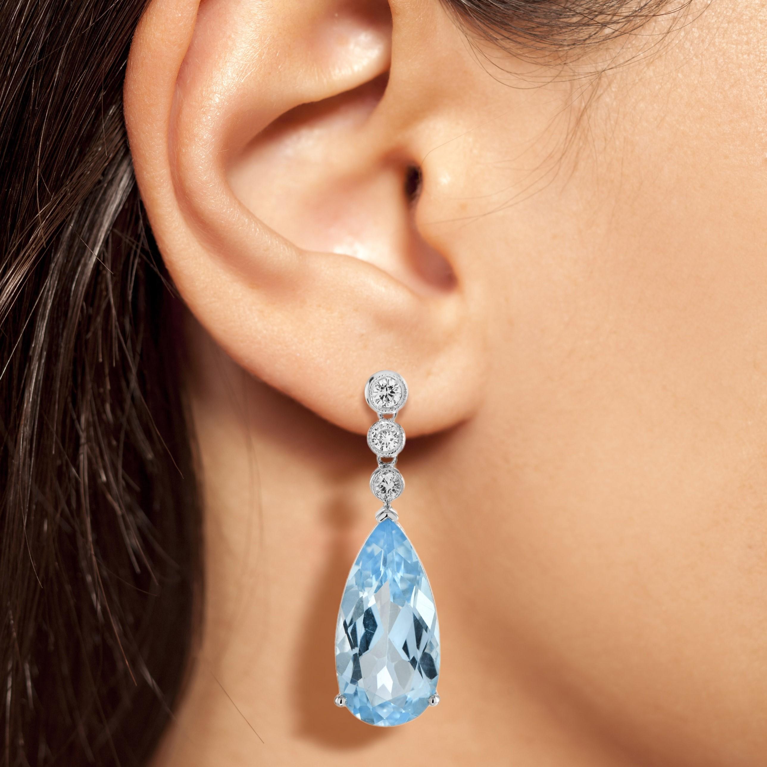The handcrafted vintage style Blue Topaz and Diamond Drop Earrings feature a pair of pear-shaped topaz in a sky blue hue set in a fine claw setting. These settings are elegantly hanging from diamond set stud fitting. The earrings are incredibly