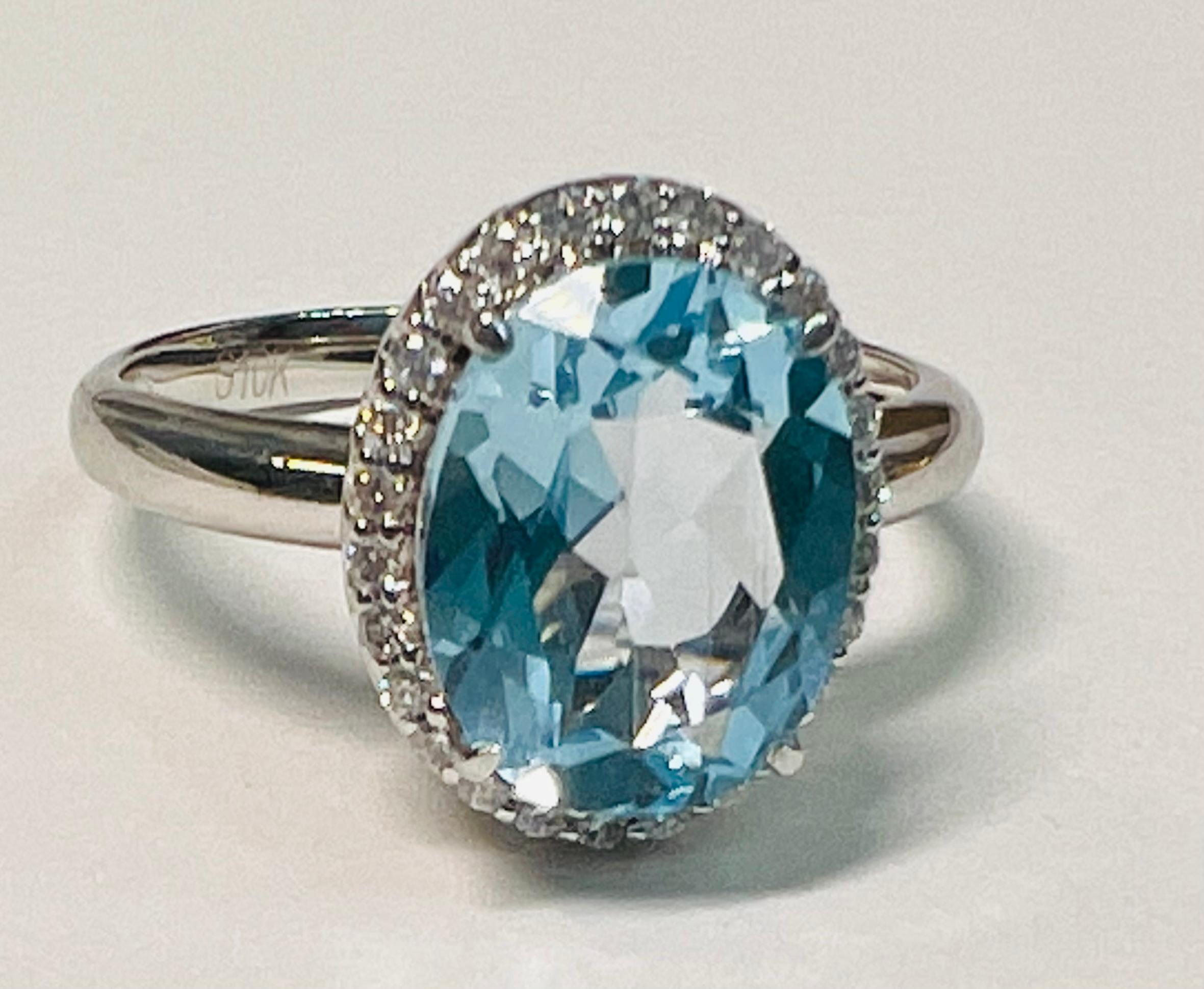 3,45ct Baby Blue Oval Topaz mit .2ct Halo aus Diamanten. Fassung aus 10k Weißgold. 
Dieses beeindruckende Stück ist der perfekte Verlobungsring oder Jubiläumsring. Der ovale 3.45-karätige Blautopas wurde im Rosenschliff gefertigt, um den Glanz und