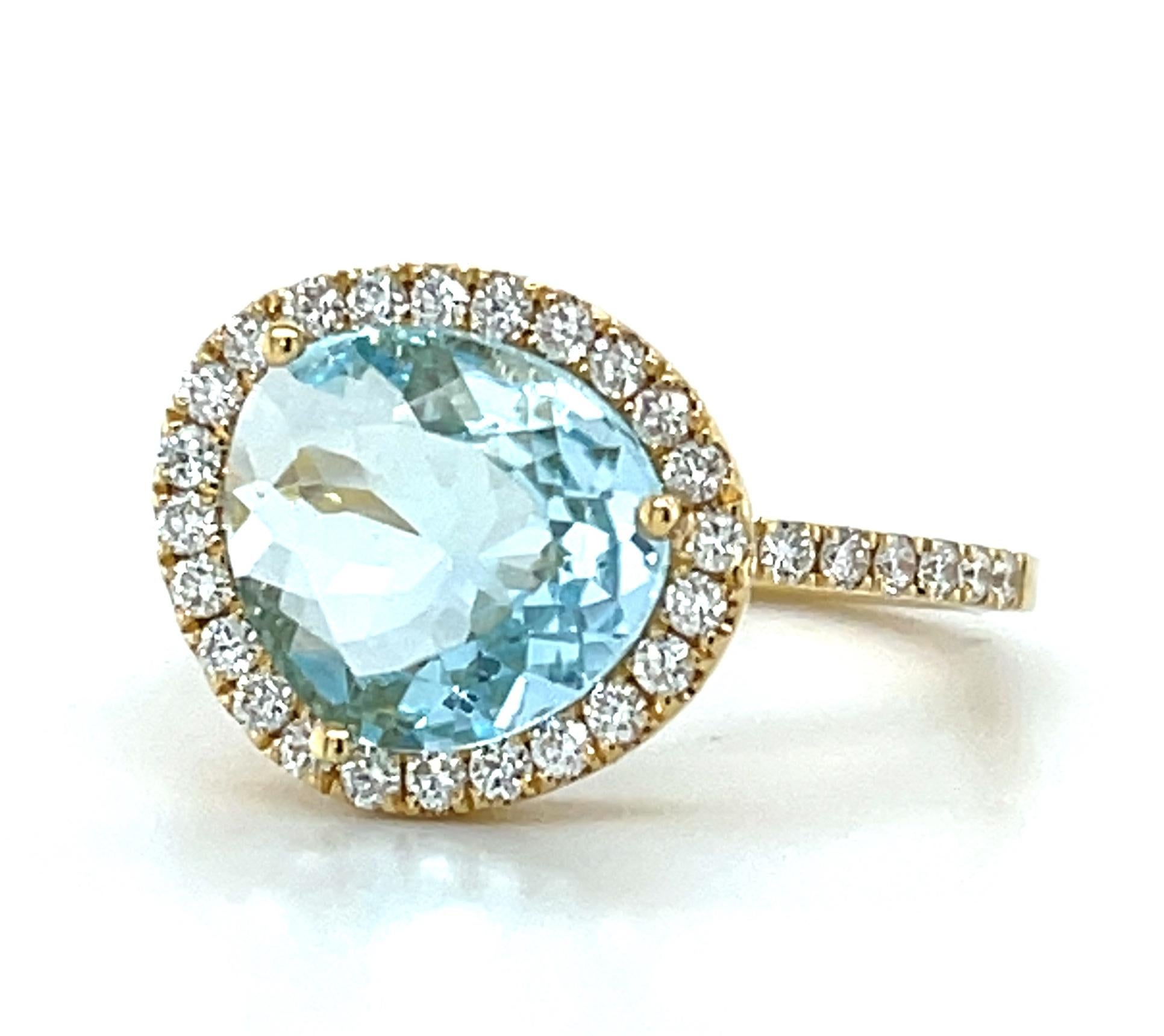 Cette élégante bague en or jaune 18 carats présente une magnifique topaze bleue cristalline encadrée d'un halo de diamants blancs étincelants. La topaze bleue de 2,70 carats a une couleur bleu ciel étonnante et est taillée en forme d'oignon, une