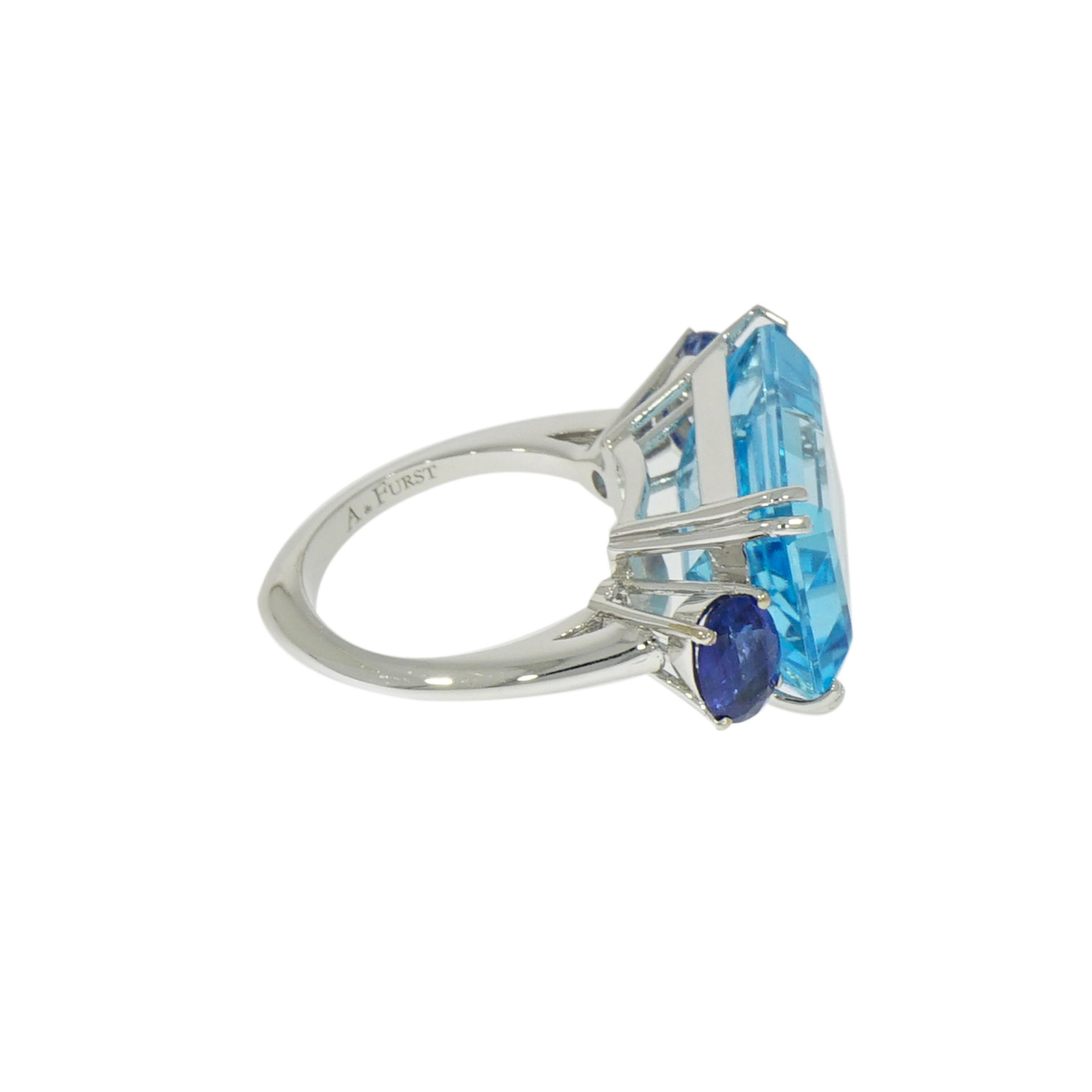 Dive into the clear blue hue of this beautiful cocktail ring... Inspired by the bright colors of summer and the essential lines of modern architecture, translated into the bold emerald cut center stone with oval accent.  
This Blue Topaz and Kyanite