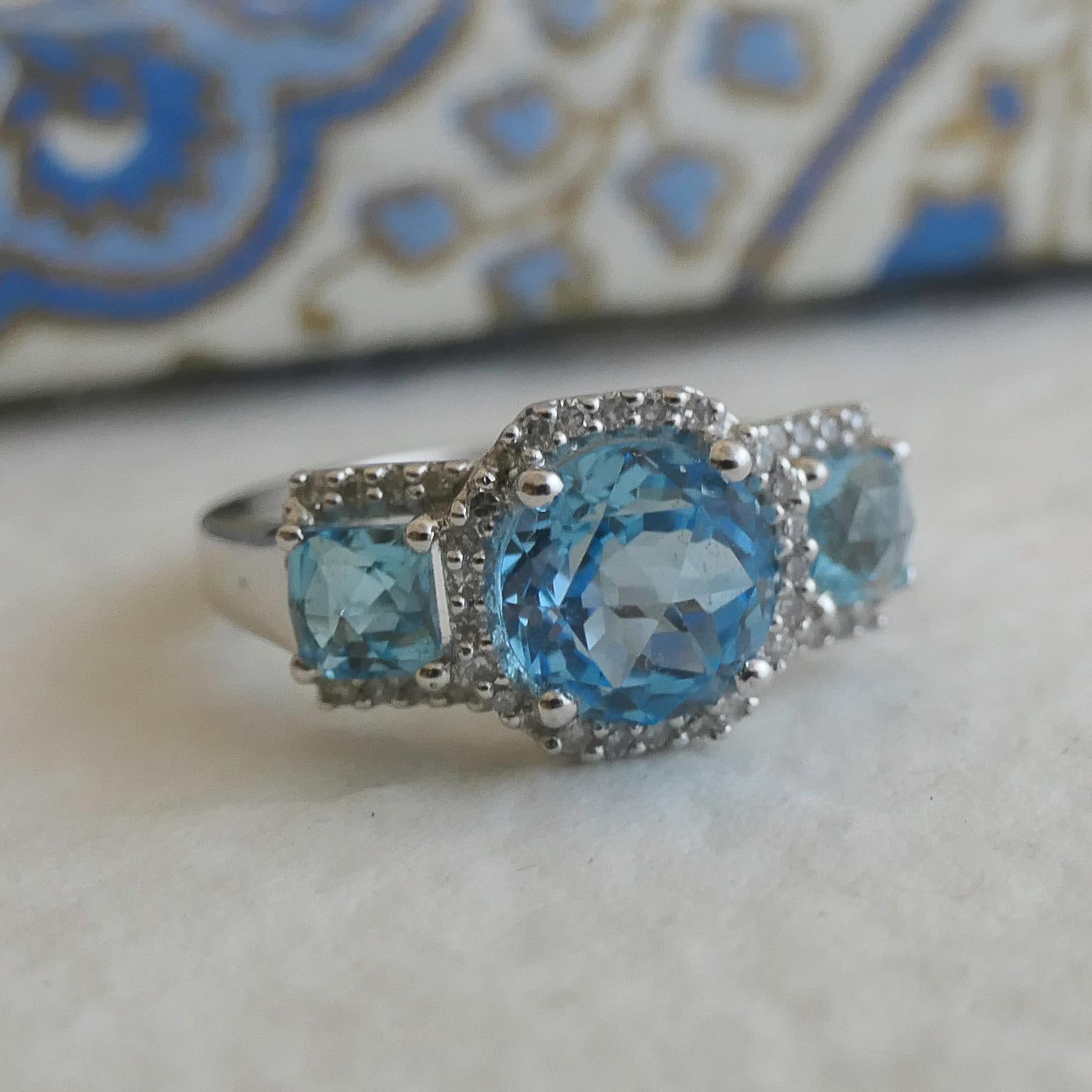 Blauer Topas und Diamanten in 14-karätigem Weißgold, gestempelt 585, in Zackenfassung.
Band ist ca. 2,8 mm Das Gewicht des Ringes (einschließlich Steine) ist 5,7 Gramm.

✦Edelsteine: Blautopas und Diamant
✦Steinschliff: Facettiert Rund in der Mitte