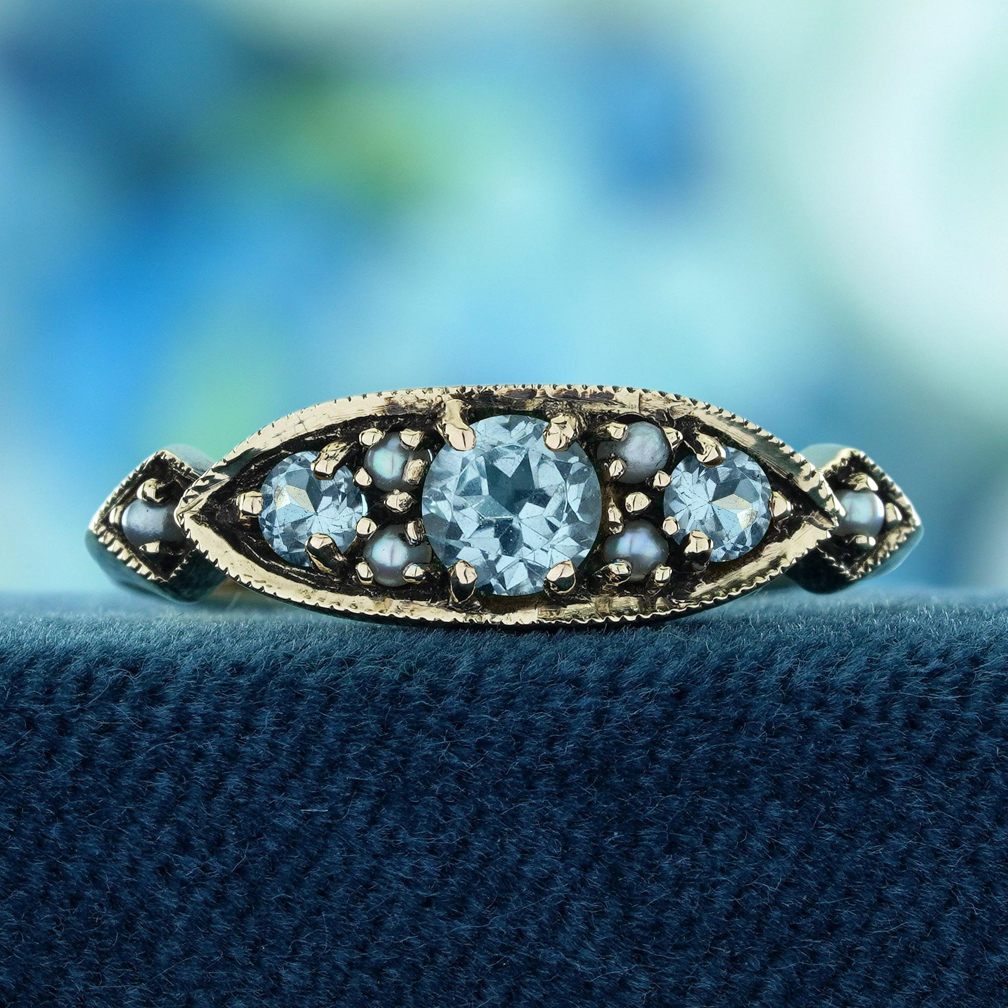 Aggiungi un tocco di eleganza senza tempo alla tua collezione con il nostro anello a grappolo in stile vintage con topazio blu naturale e perla, splendidamente realizzato in oro giallo massiccio 9 carati. 
Questo squisito pezzo mette in mostra la