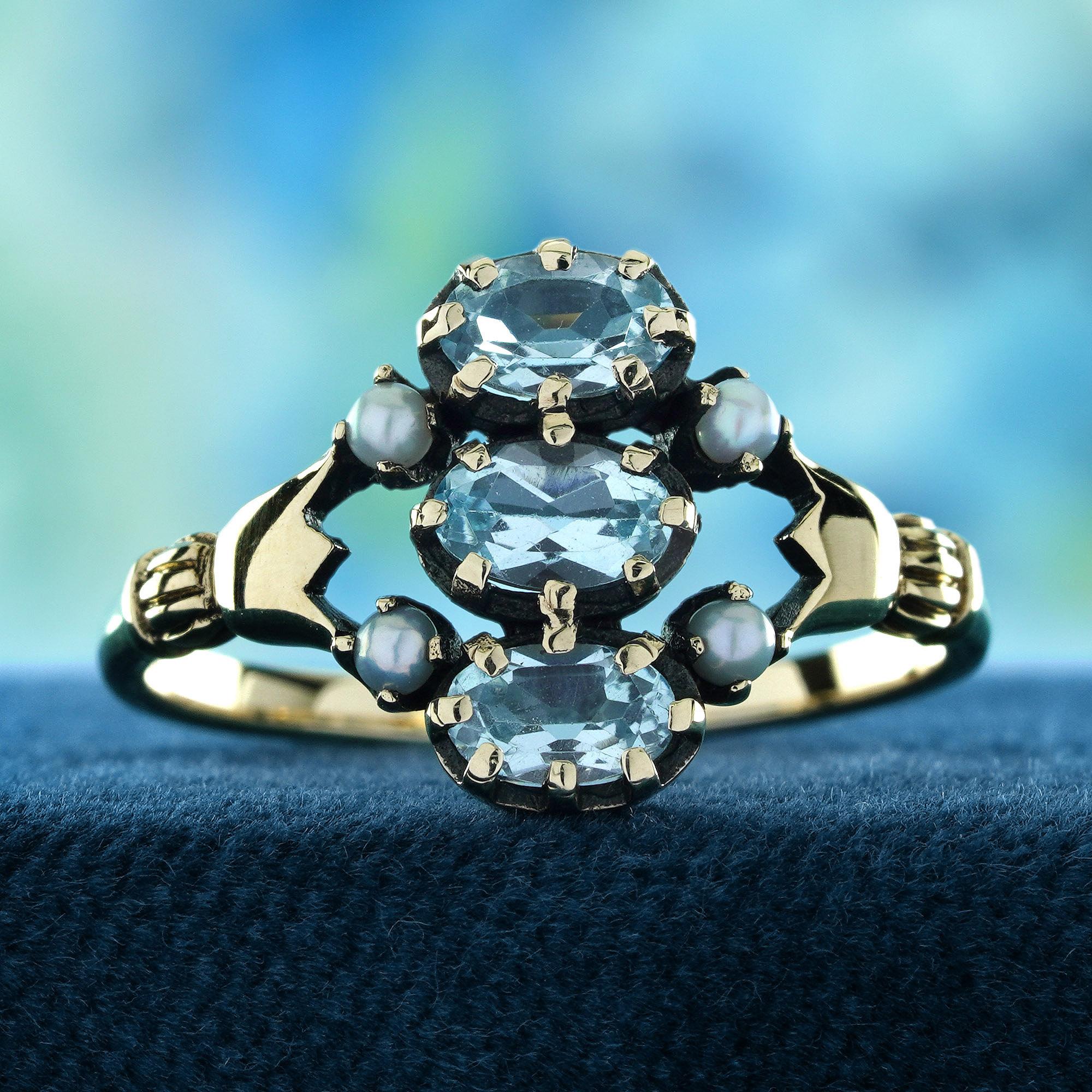 The Natural Blue Topaz and Pearl Vintage Style Three Stones Ring features a row of beautiful blue topaz stones, perfectly aligned at the center. Flanking the topaz are four lustrous pearls, enhancing the elegance and adding a touch of classic charm.