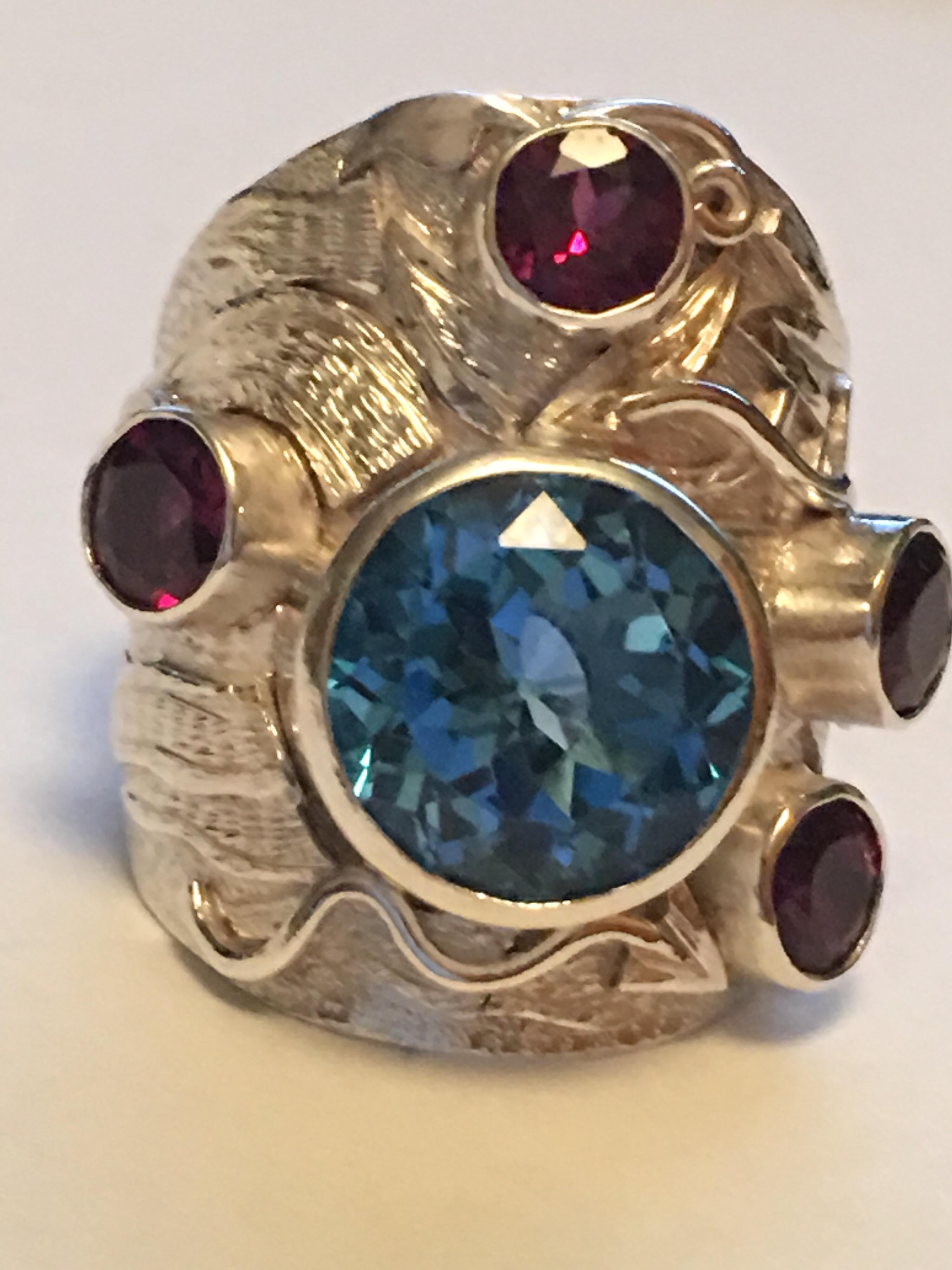 Round blue topaz 13 MM AND Round Garnet 5 MM Set in sterling silver is hand crafted ring,
This one of a kind Ring is master piece work .
All the stones are hand cut and polished. 
The ring is size 9 , If needed you can resize it.
