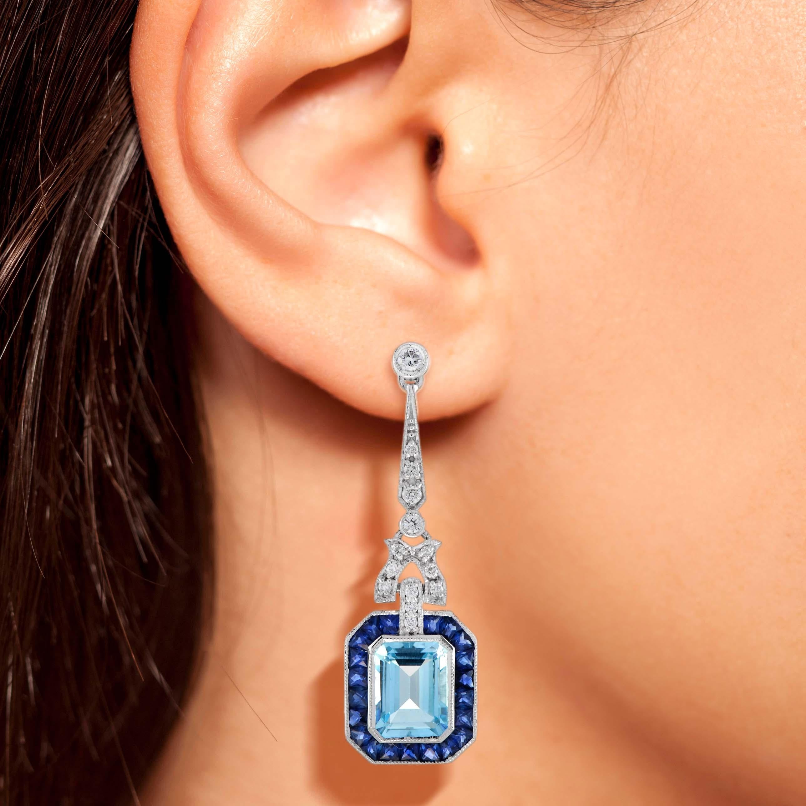 A pair of emerald cut blue topaz stones, precisely matched by eye, totaling 5.90 carats, and set into a pair of exquisite drop ear studs. These exquisite earrings are complimented by 3.78 carats of French cut blue sapphire and round diamonds