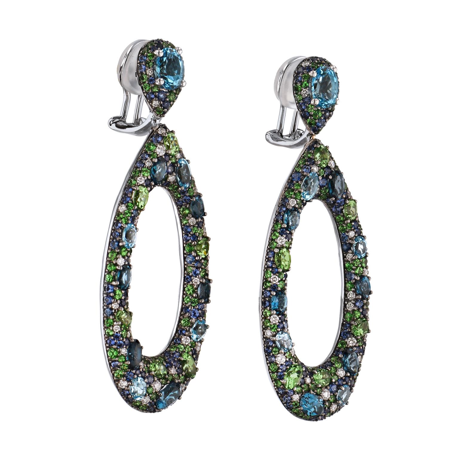 Show your fashion forward style with these intricately designed earrings, set with 6.99 carats of Blue Topaz, joined with dangling 18 karat white gold black rhodium plated teardrops adorned with a scattered variety of sapphires (3.04 carats in total