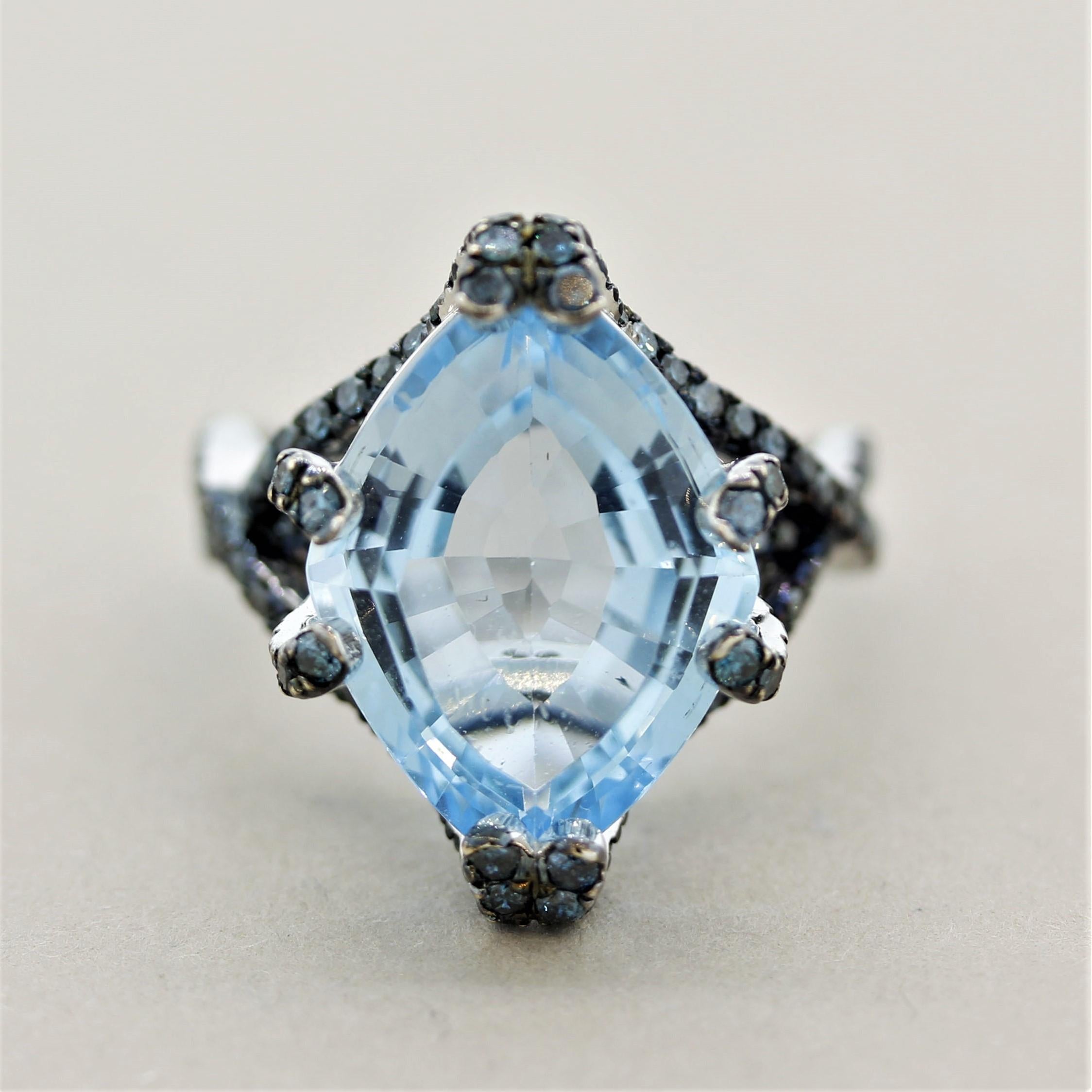 Simply a different ring made in a modern sexy style. It features a 10.70 carat diamond-shaped blue topaz set in the center with unique prong fixtures. It is complemented by 1.30 carats of blue diamonds set on the sides of the ring and running up the
