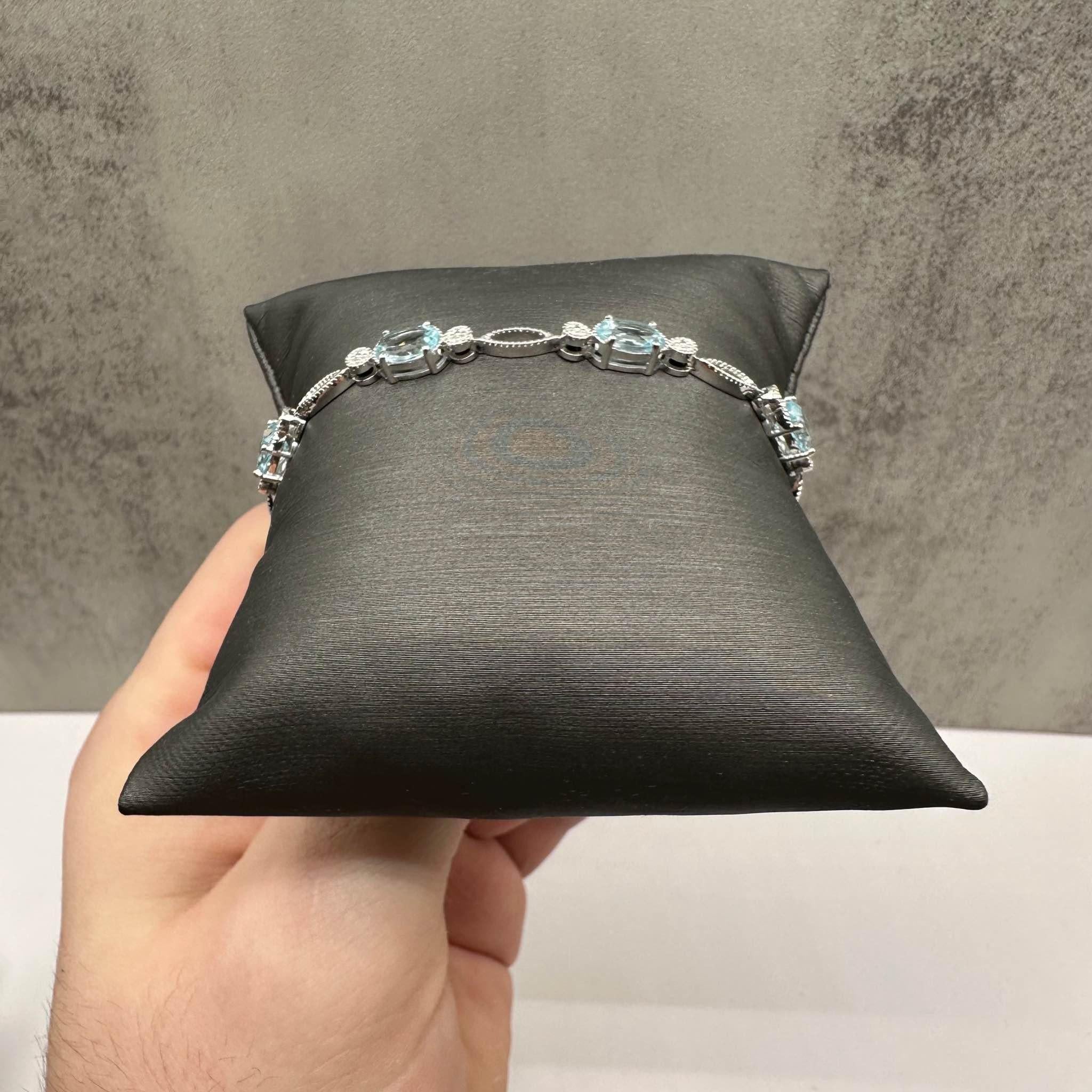 This stunning Blue Topaz Bracelet in sterling silver features five 7x5mm oval blue topaz stones, offering a vibrant and elegant look. With a length of 7 3/8 inches, it fits comfortably on the wrist, making it perfect for both casual and formal