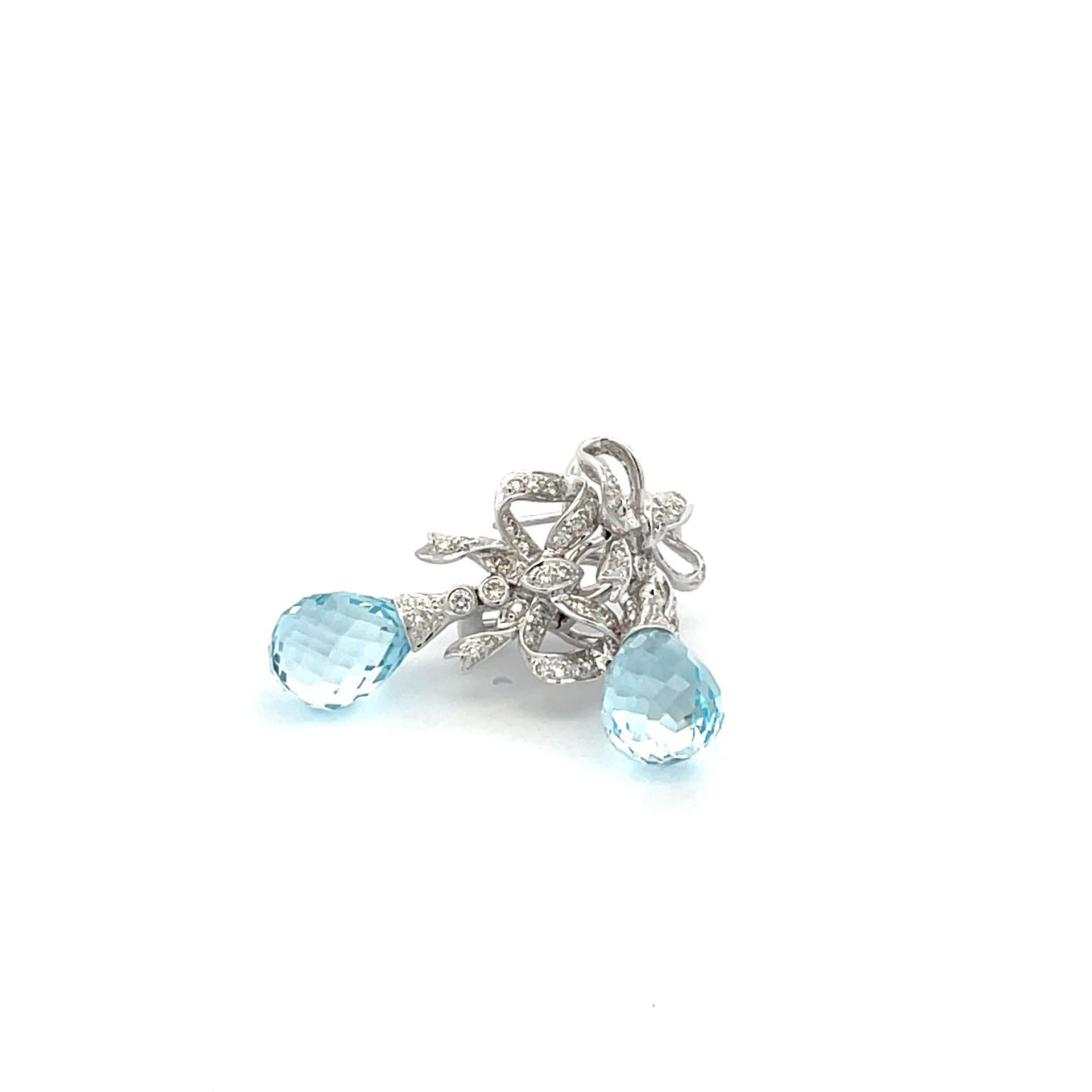 Blue topaz bow earrings set in 18 karat white gold featuring 2 briolette cut blue topaz and white diamond accents  with a straight post and omega clip system. 

60 brilliant cut diamond  0.78ct total weight

2 blue topaz briolette 15.80ct total