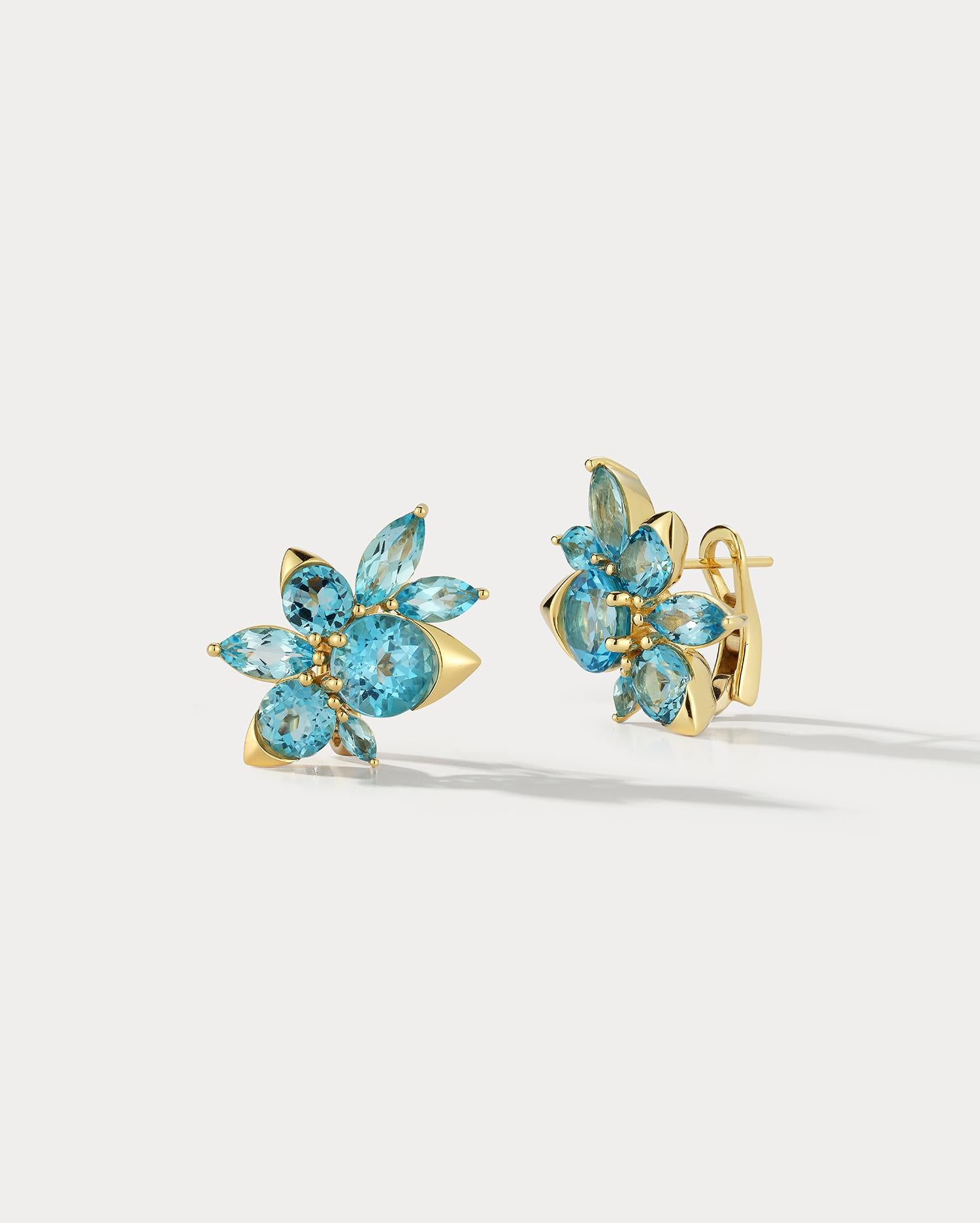 These 18K yellow gold earrings feature a cluster of dazzling blue topaz stones that sparkle in the light. Each stone is expertly prong or bezel set, adding to the overall elegance of the design. The yellow gold provides a warm and inviting contrast