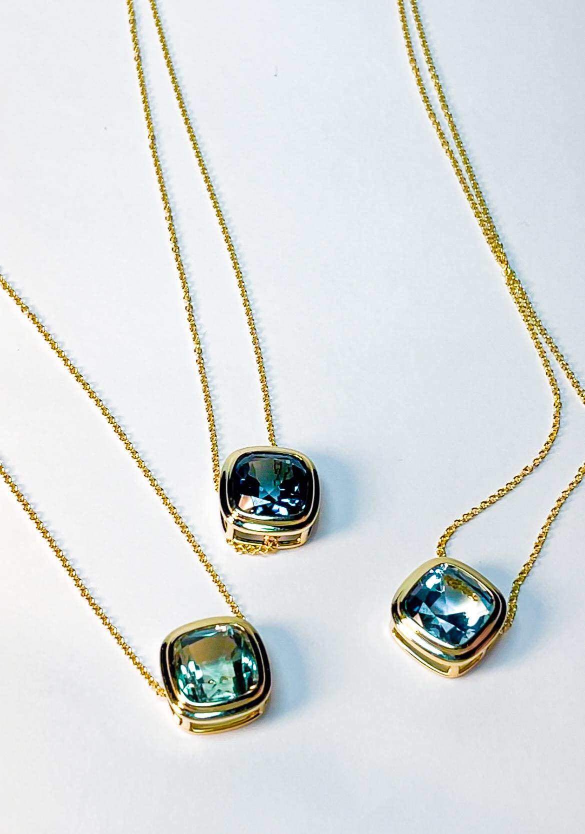 This elegant pendant showcases a 9x9 mm cushion-cut blue topaz, weighing approximately 4.18 carats, set in 18K yellow gold. Measuring 0.48 inches in both length and width, it comes with an 18-inch chain, making it a timeless and sophisticated