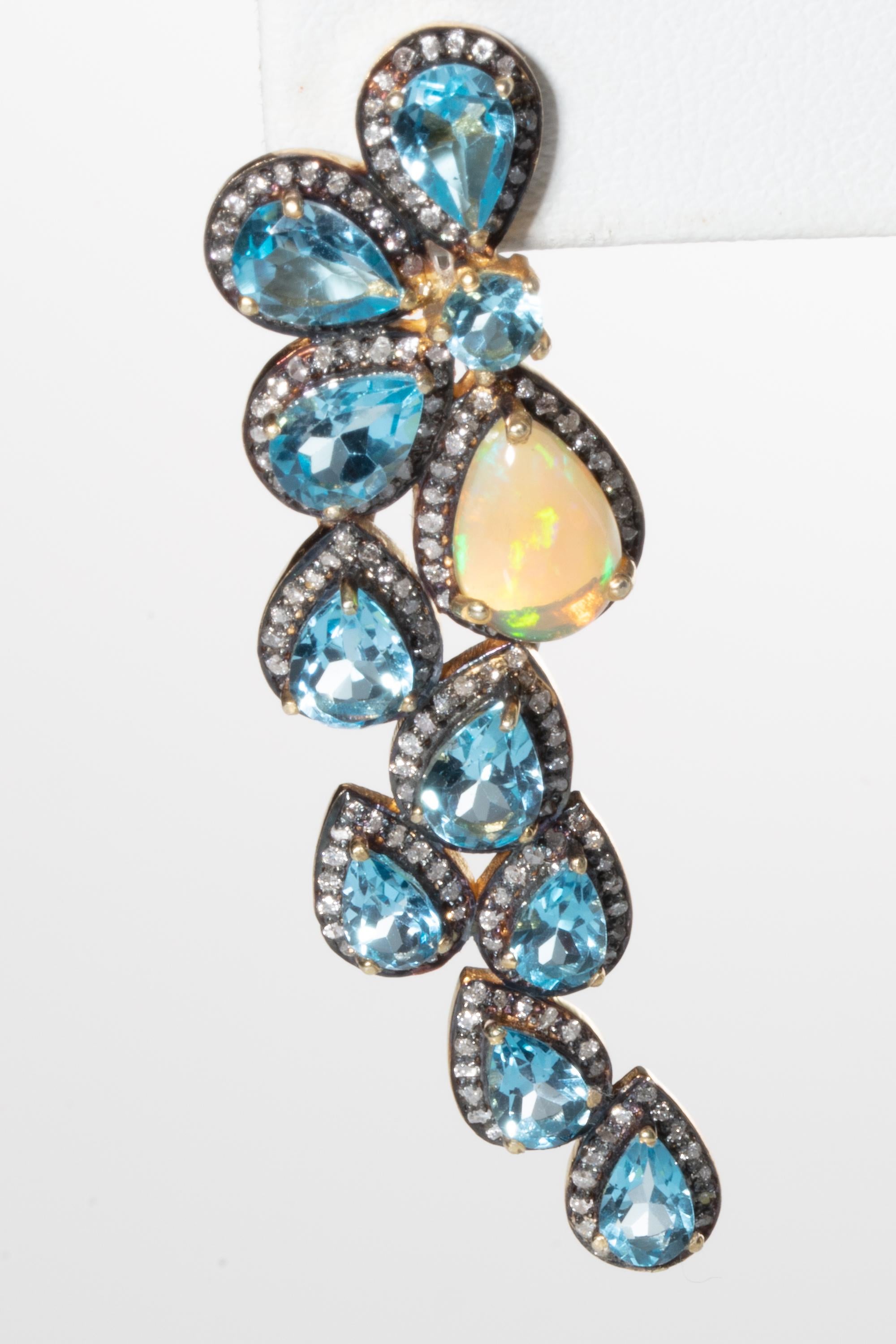 A fabulous pair of faceted, pear-shaped blue topaz gemstones bordered in pave`-set diamonds and featuring one pear-shaped opal on the inside of the cluster.  Set in an rhodium plated sterling silver providing that dark contract against the diamonds.