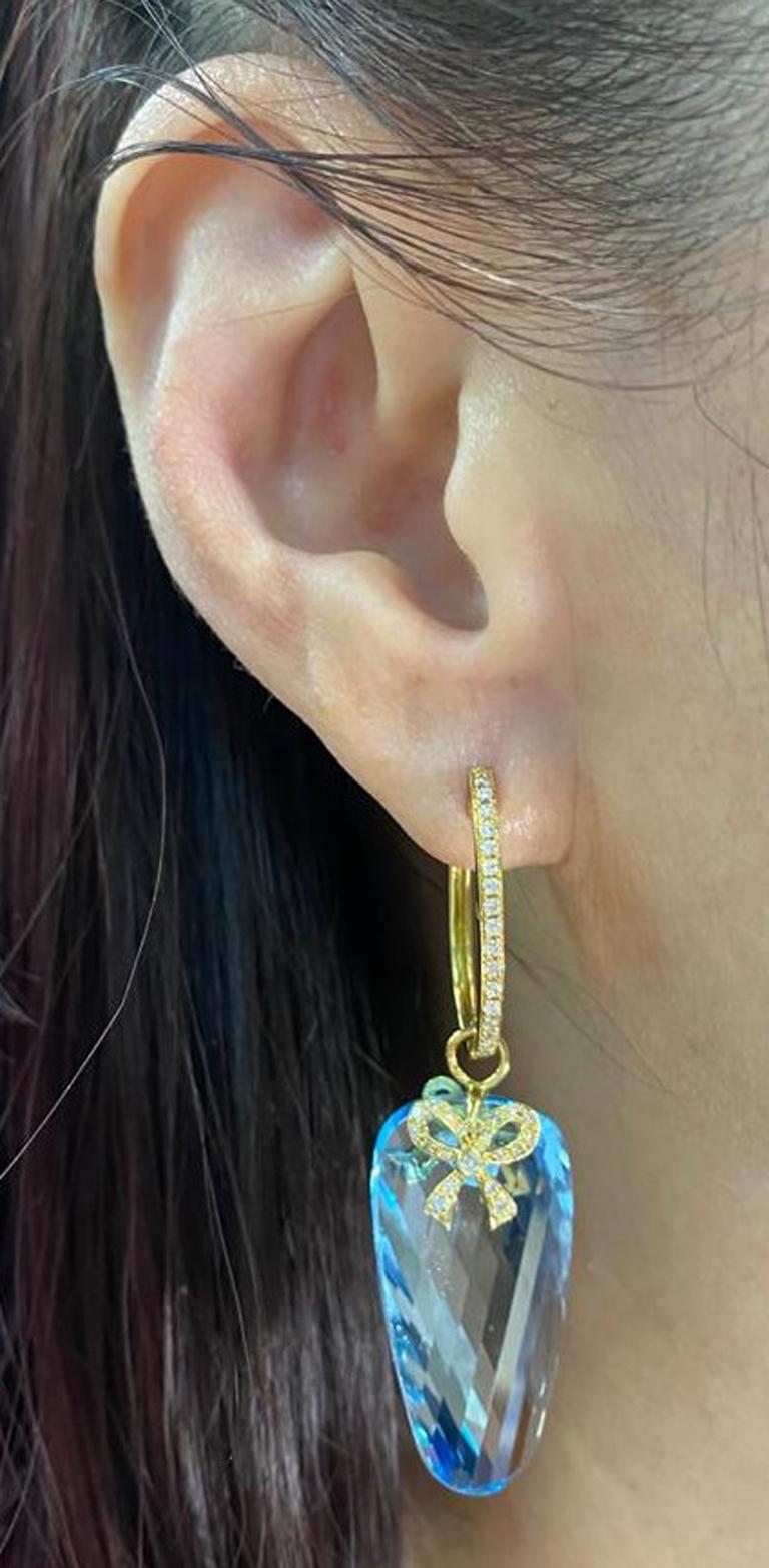 This earring features 2 blue topaz weight 79.29 carats, on top of the blue topaz are set with 2 yellow gold and diamond ribbons. This earrings combined for 0.49 carats of white round diamonds. Earrings are set in 18 karat yellow gold.

18 Karat