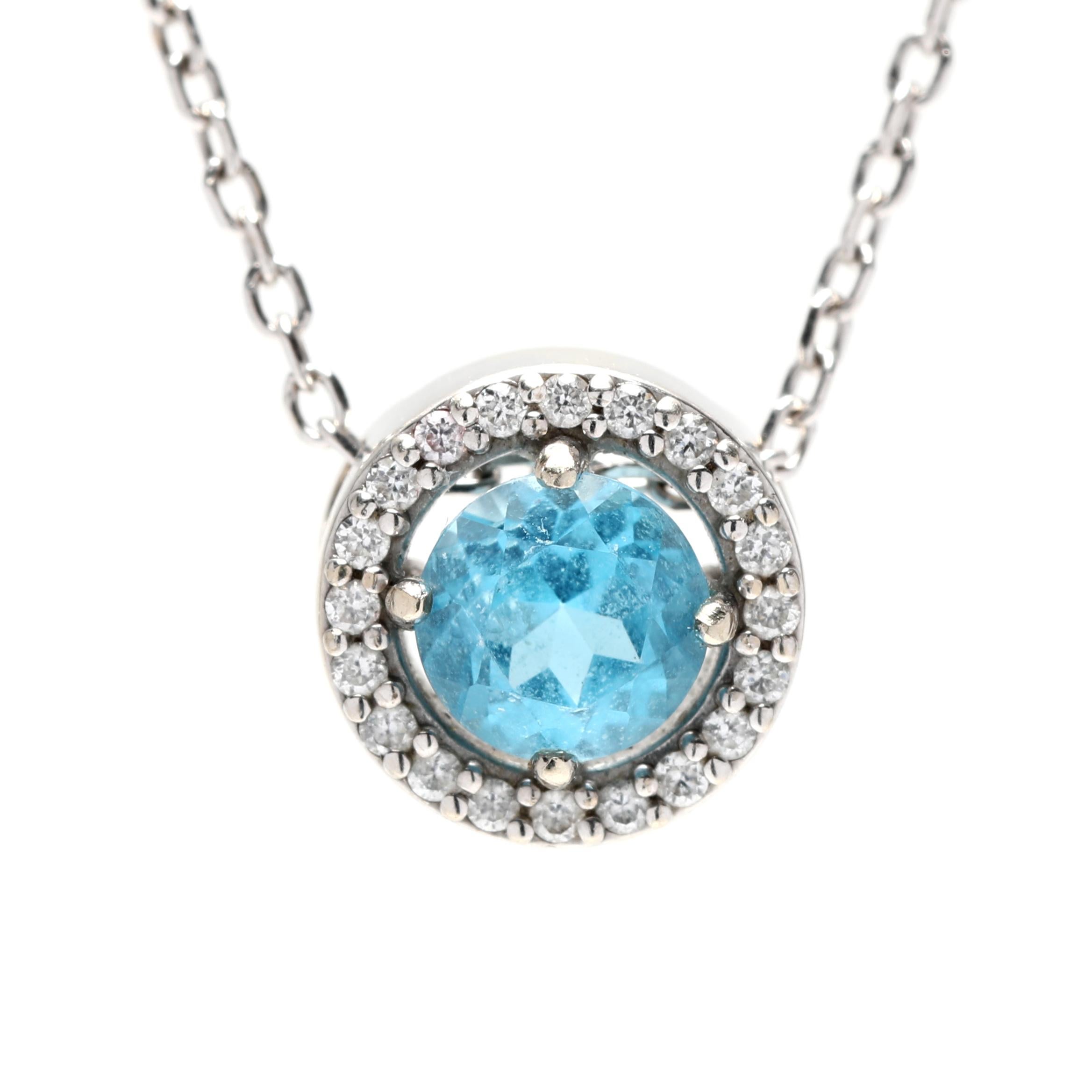 Ce collier pendentif exquis présente une superbe topaze bleue, entourée d'un halo de diamants scintillants. Réalisé en or blanc 14 carats, ce design élégant est parfait pour toute occasion et constitue un magnifique collier de pierres de naissance