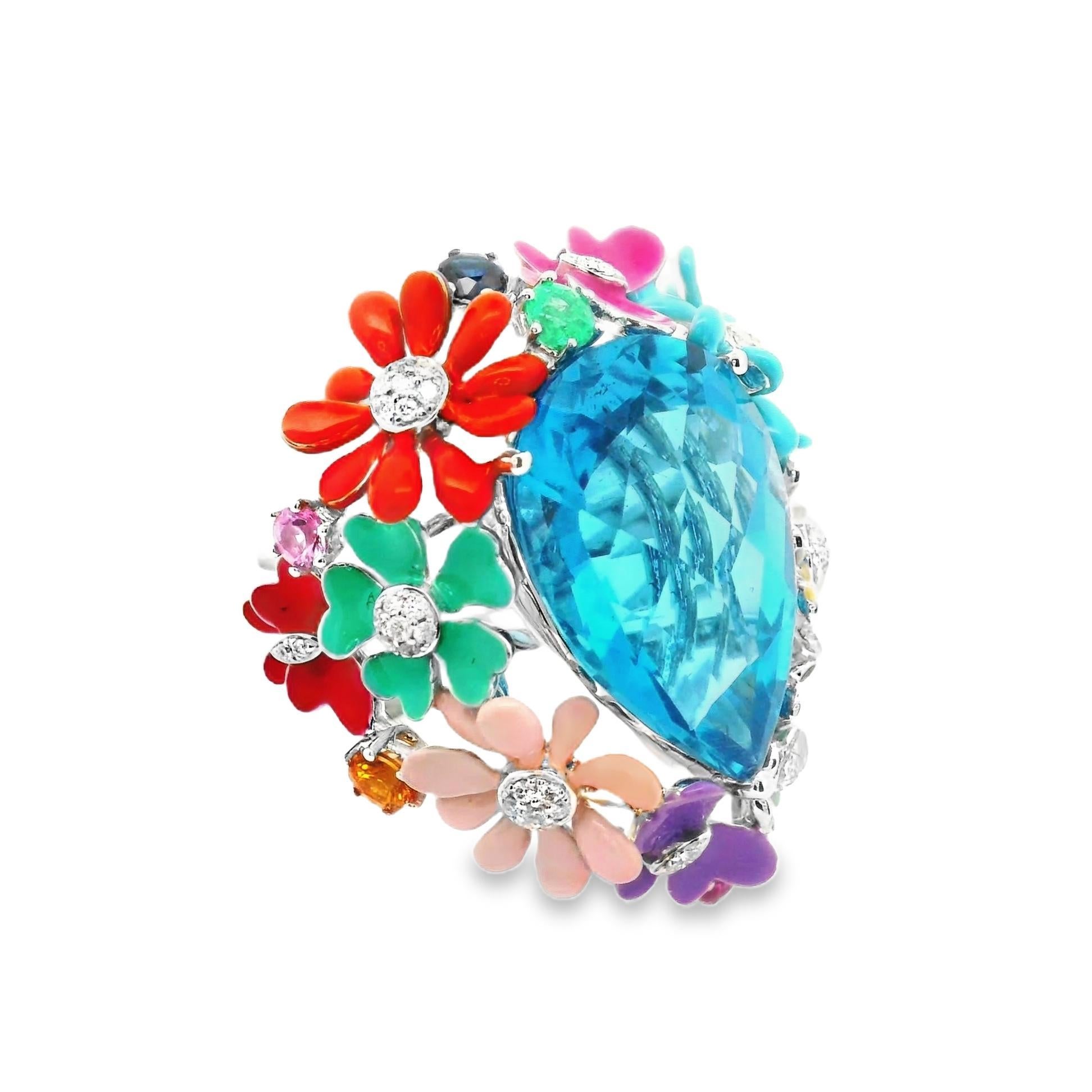 A bright and colorful cocktail ring featuring a pear-shape blue topaz weighing 16.69 carats. It is surrounded by a garden of flowers and butterflies which are enameled in various vibrant colors that all pop. The flowers and butterflies are also set