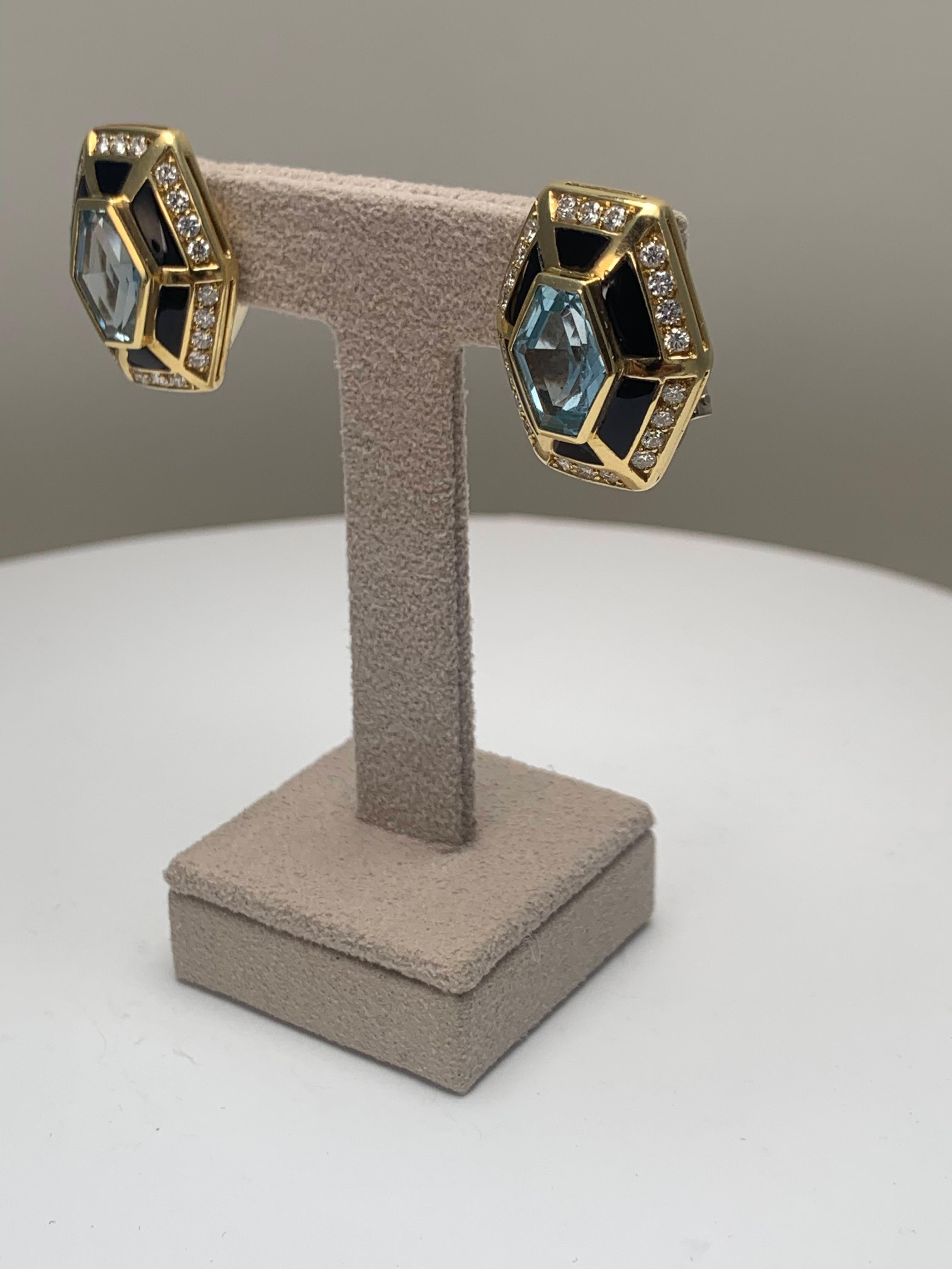 Questi orecchini a clip presentano un'audace struttura geometrica. Al centro di ogni orecchino c'è un topazio blu, incorniciato da segmenti di onice meticolosamente posizionati e da un'aureola di diamanti rotondi taglio brillante incastonati.