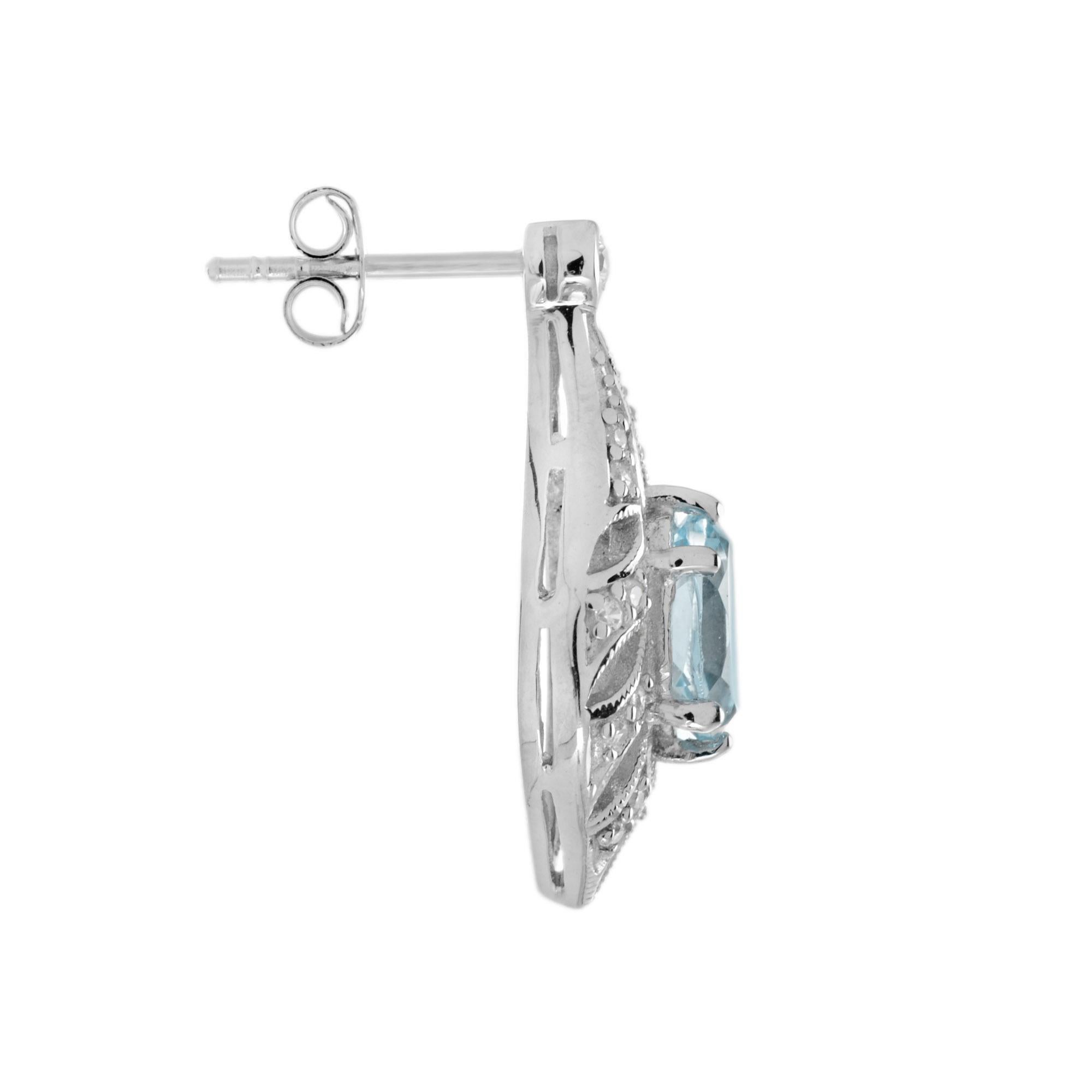 Ces boucles d'oreilles d'inspiration antique pour elle présentent des topazes bleues ovales dans d'élégantes montures ajourées de diamants ronds étincelants. Ces boucles d'oreilles en topaze bleue présentent un style Art déco antique unique qui ne