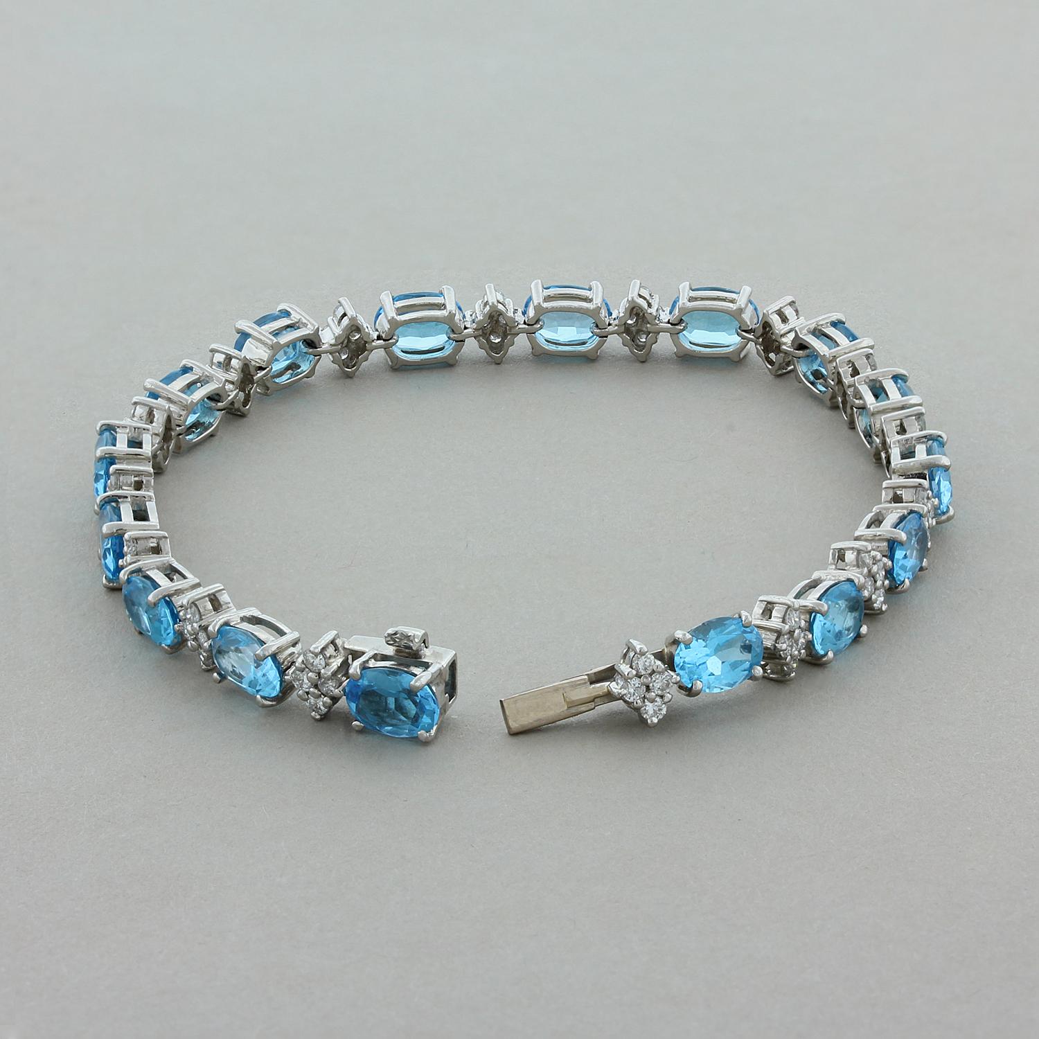 A gorgeous bracelet featuring 14.95 carats of ocean blue topaz. The oval cut blue topaz are linked with 1.30 carats of alternating diamond clusters. Set in platinum with a box clasp closure and a hidden safety latch underneath the bracelet for a