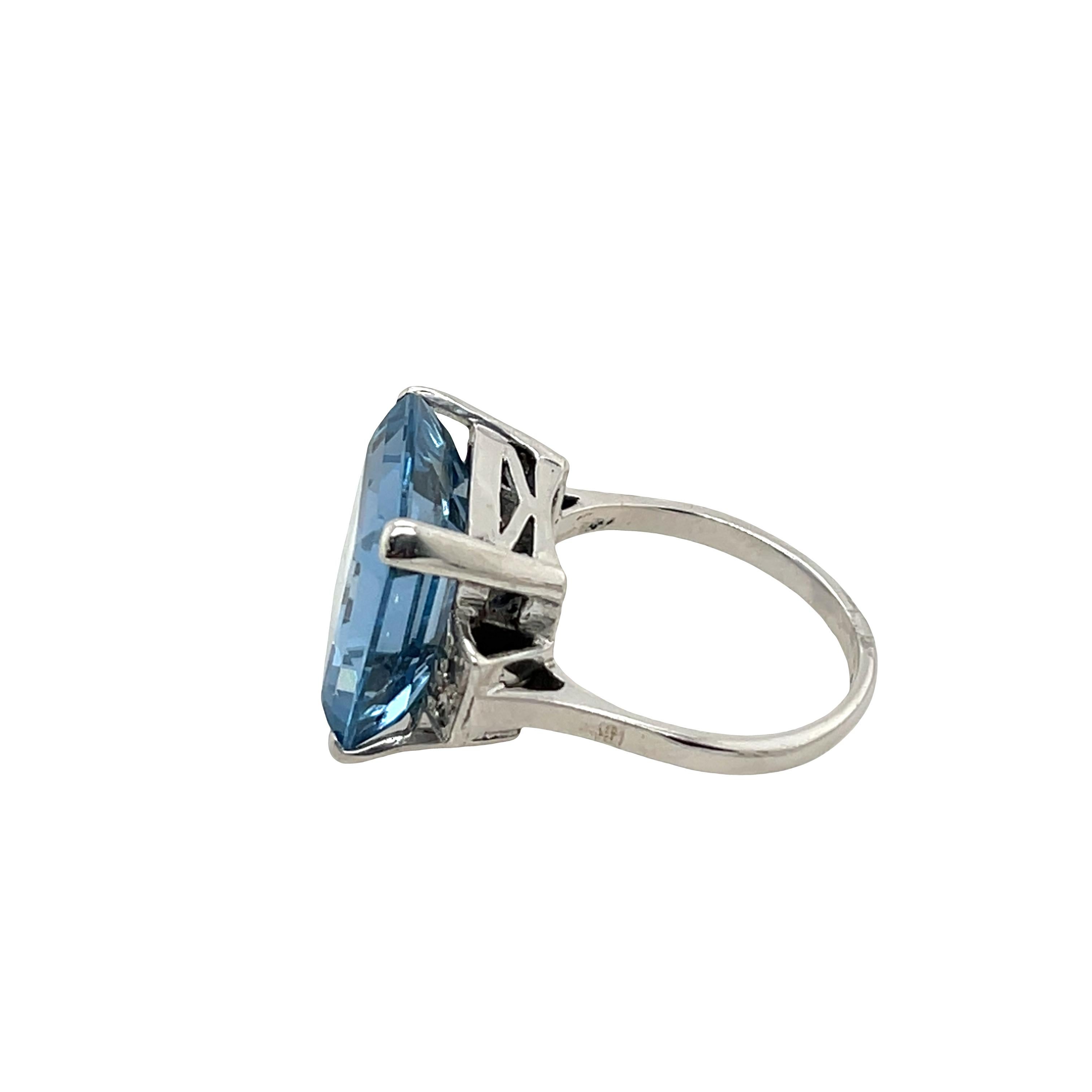Ein exquisites und zeitloses Design: Dieser elegante Ring präsentiert einen leuchtenden Blautopas als Herzstück, 
flankiert von zwei passenden runden Diamanten auf jeder Seite für ein raffiniertes und ausgewogenes Aussehen in Platin