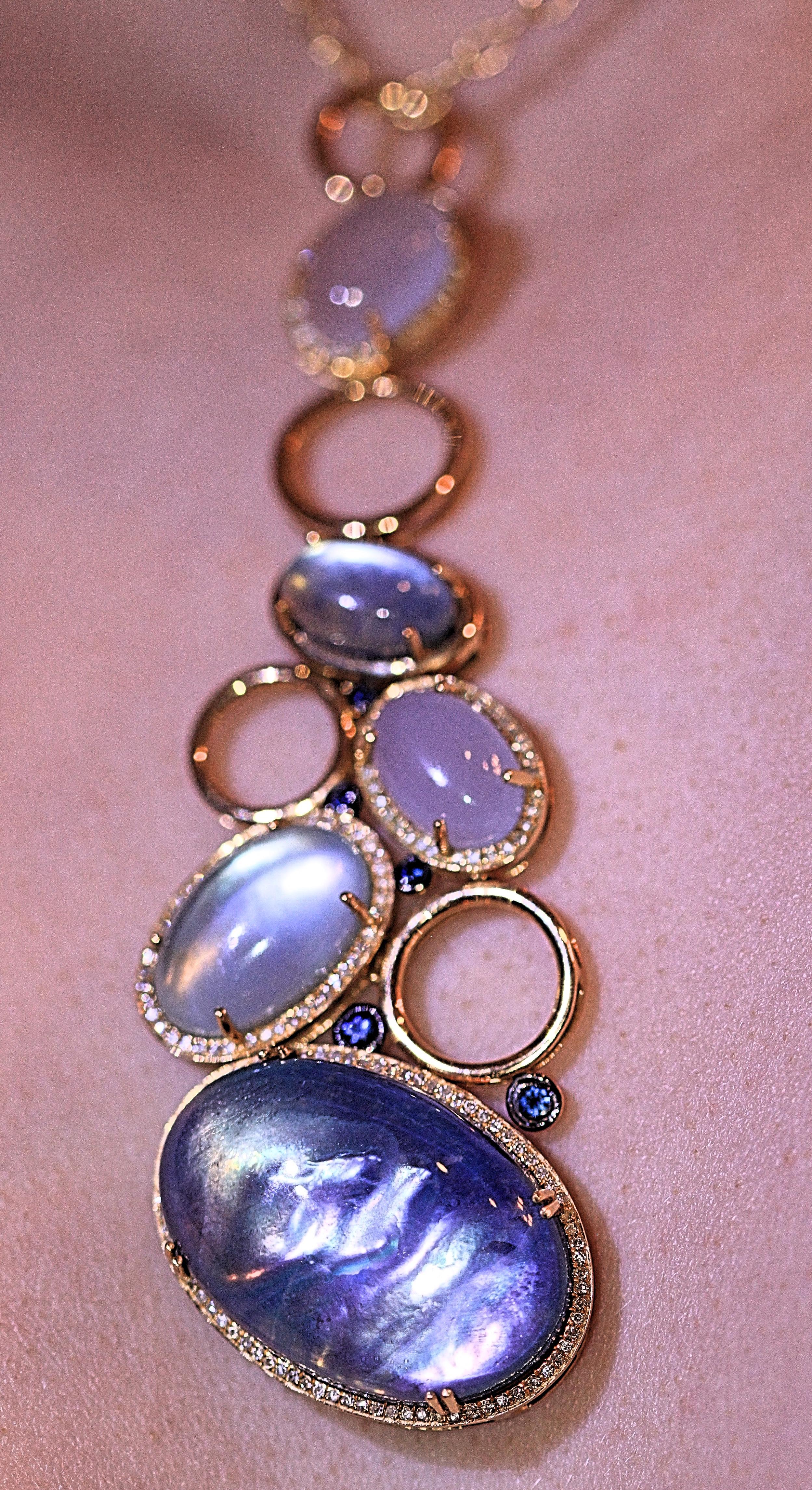 A unique large attention getting necklace.  It has five beautiful oval semi precious stones that are different shades of blue.  The pendant has five small accent sapphires and the piece measures 3 3/4 inches long with a chain that measures 16 inches