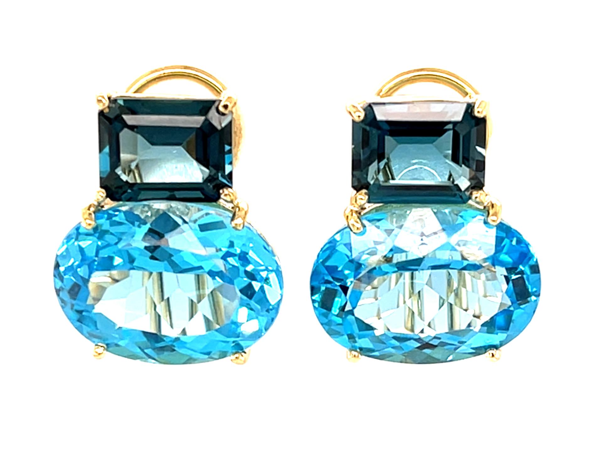 Ces boucles d'oreilles françaises à clip présentent plus de 28 carats de magnifiques topazes bleues suisses et de topazes bleues de Londres serties dans des boucles d'oreilles en or jaune 18 carats fabriquées à la main. Les topazes bleues de
