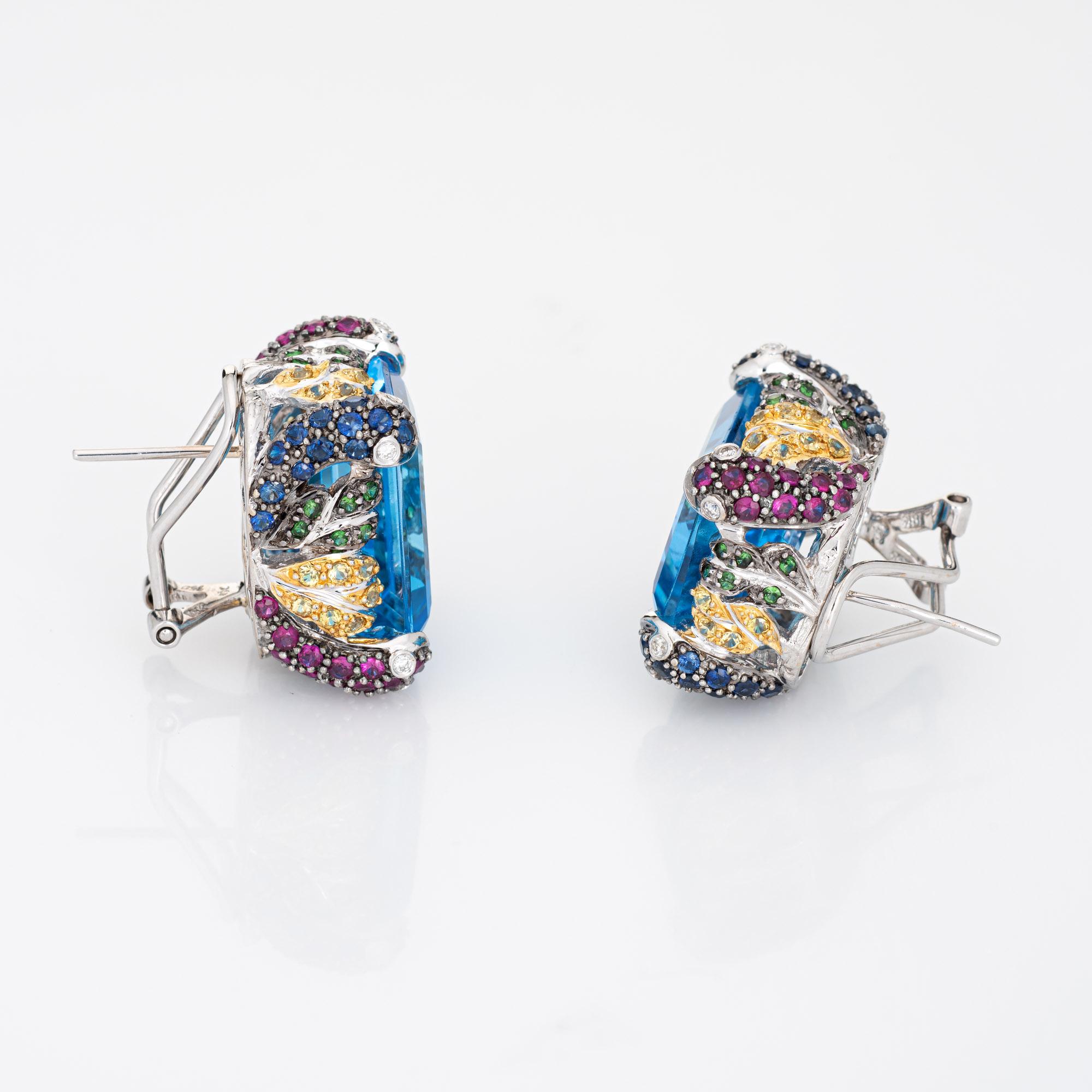 Dramatic pair of estate blue topaz, diamond & gemstone earrings crafted in 18k white gold. 

Emerald cut blue topaz measures 18mm x 13mm each (estimated at 16 carats each - 32 carats total estimated weight). Rubies, tsavorite garnets, yellow & blue