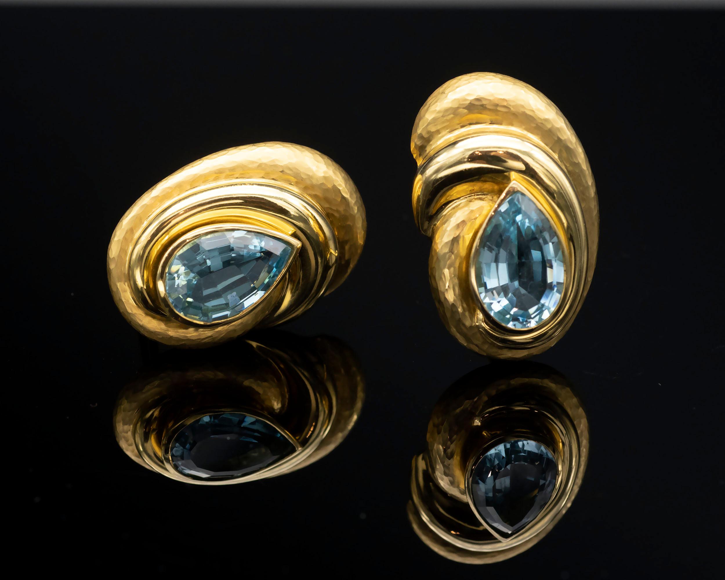 Delightful earrings: A swirl of hammered and polished solid 18-karat gold showcasing a pear shape blue topaz.  These topaz have a really beautiful color and look like nice aquamarines (not the oversaturated blue). The make is excellent.
Weight: 26.7