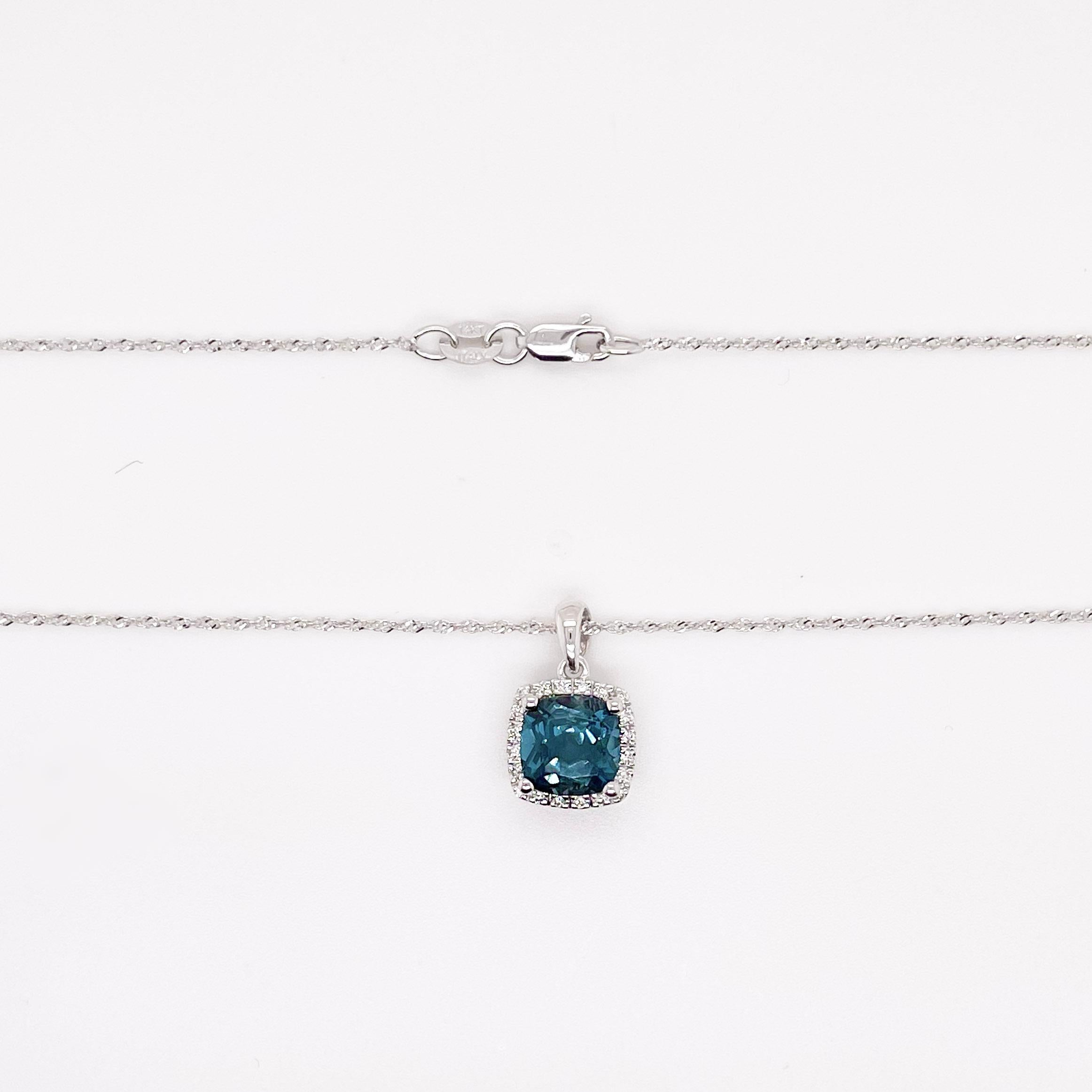 Cette topaze bleue de minuit en forme de coussin a une couleur incroyablement vibrante qui est rendue encore plus belle par le halo de diamants. Le pendentif se marie parfaitement avec la délicate chaîne en corde de bébé à laquelle il est suspendu.