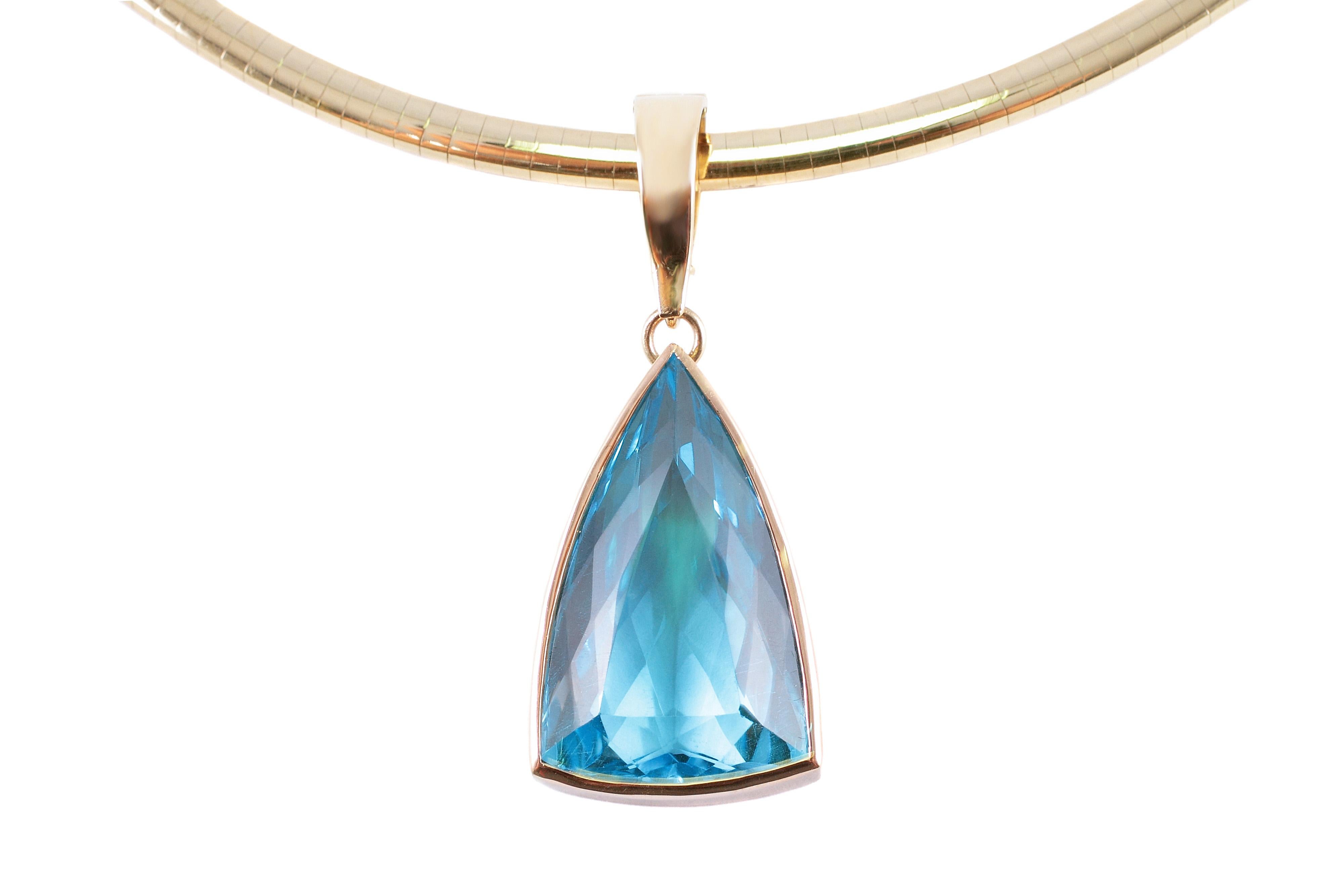 Striking blue topaz trillion cut pendant on a 20 inch 14 karat yellow gold omega necklace.   