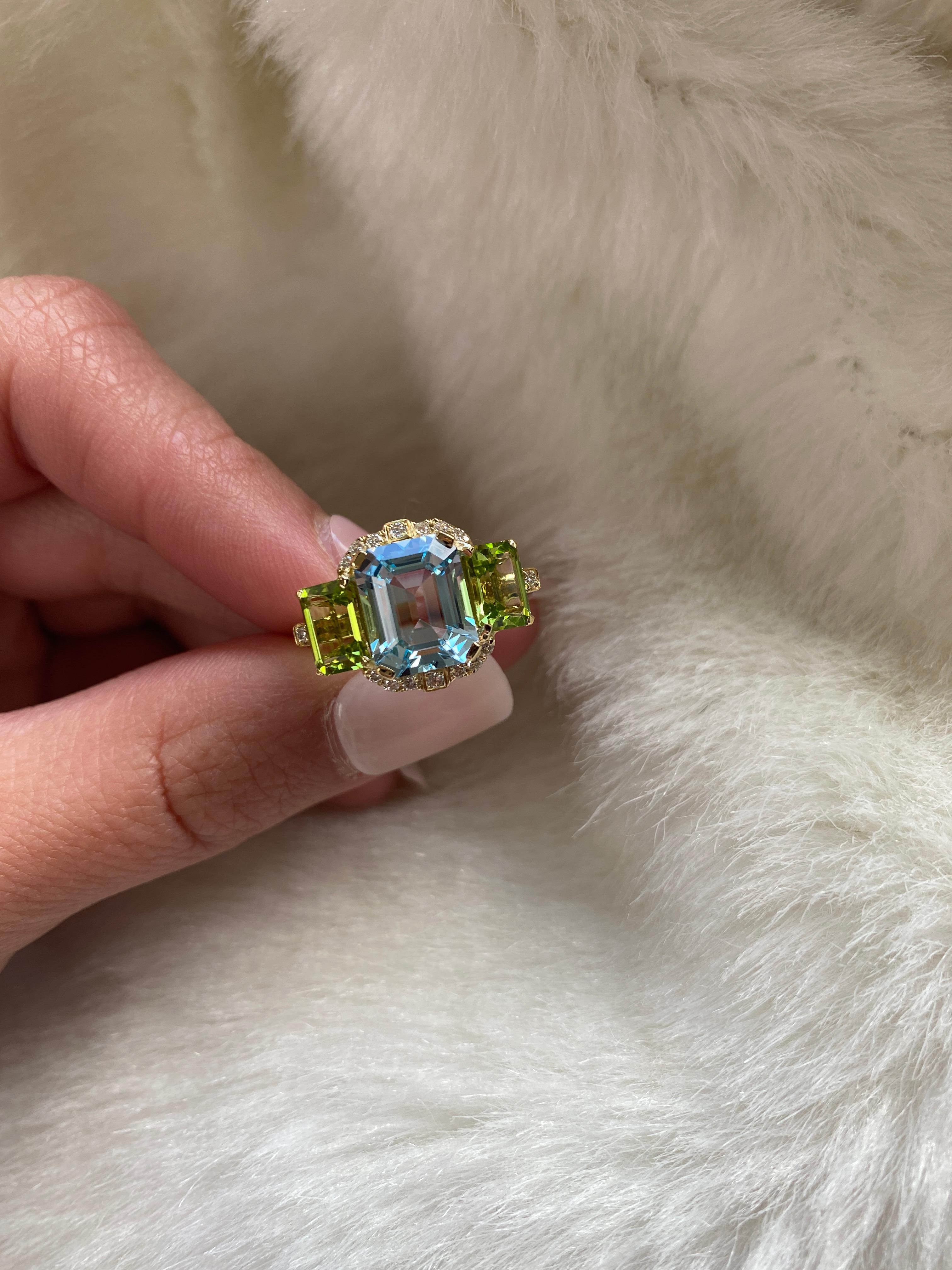 Cette bague à 3 pierres de taille émeraude avec diamants, en or jaune 18 carats, est une combinaison parfaite de topaze bleue et de péridot. Issue de notre populaire collection 