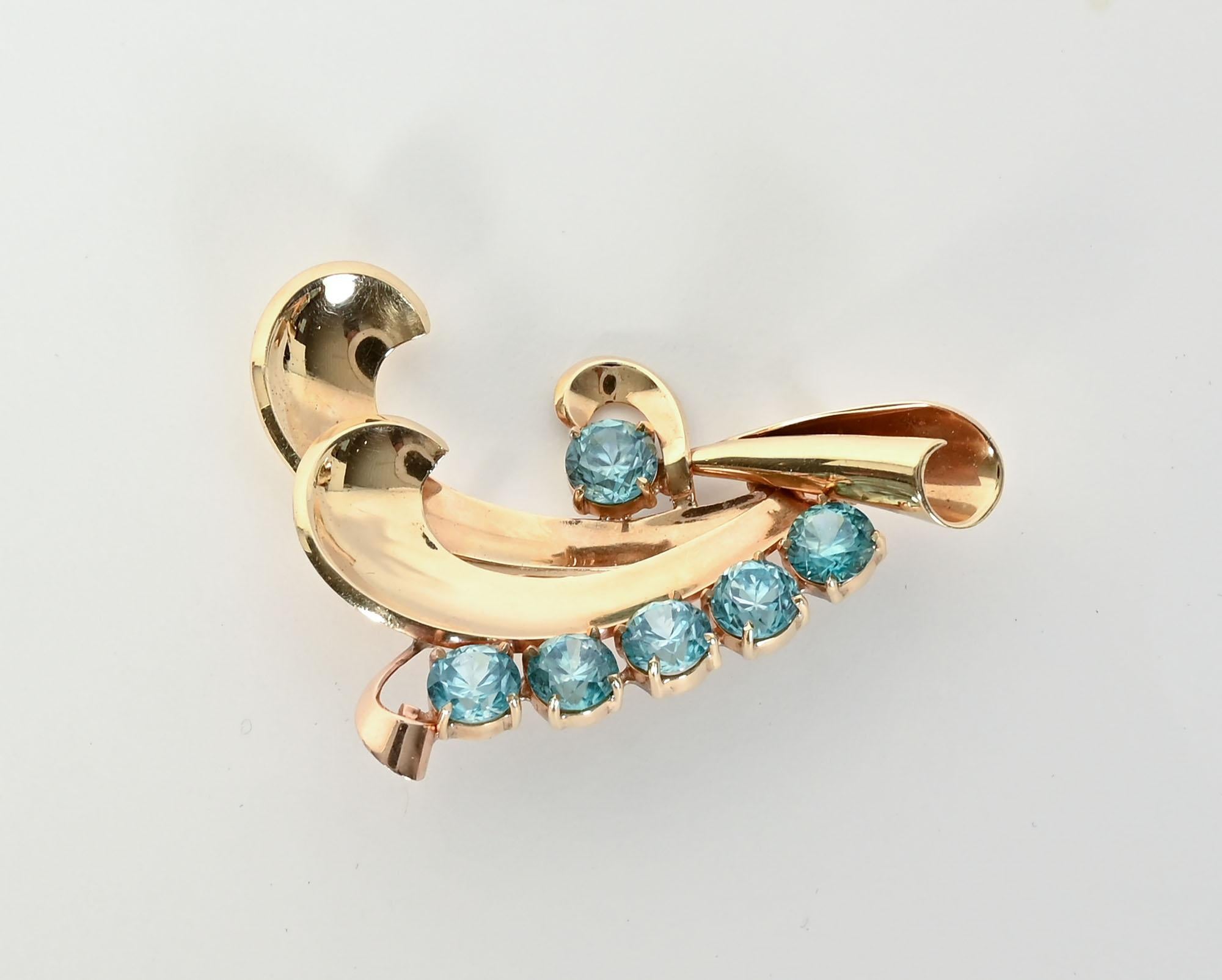 Graceful Retro brooch that can be worn in various directions. The scrolls can be up; down or on a diagonal. The 14 karat brooch is embellished with 6 blue topaz stones, each measuring 1/4 inch in diameter. The brooch has the curvilinear design