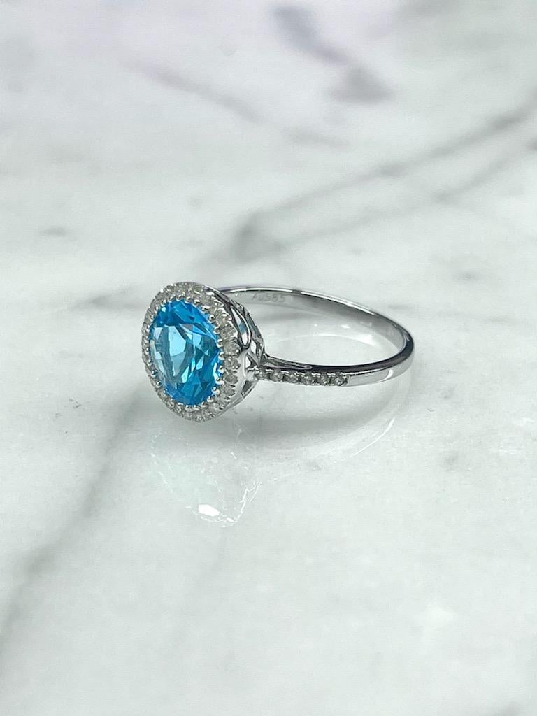 This bright blue topaz ring is a great cocktail ring!
Set in a delicate diamond halo it is sure to catch attention.  
Set with a 2.51ct Round Blue Topaz and a Diamond Halo with Diamonds down the band.