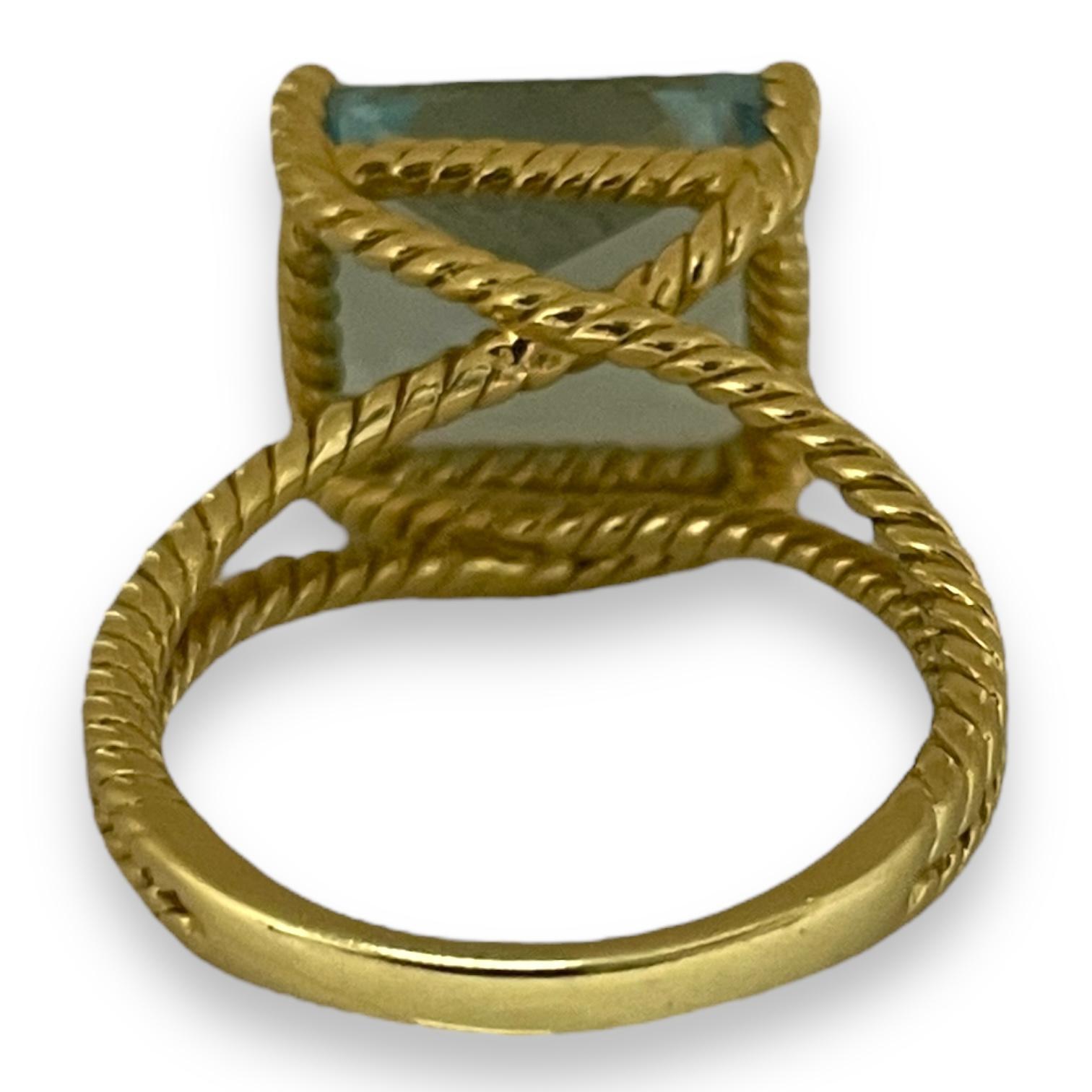 Une topaze bleue rayonnante, telle une goutte d'eau de l'océan le plus clair, bercée dans un anneau d'or jaune unique et torsadé, cette bague est une délicate combinaison de force et de beauté. Le design complexe de style corde accentue l'éclat de