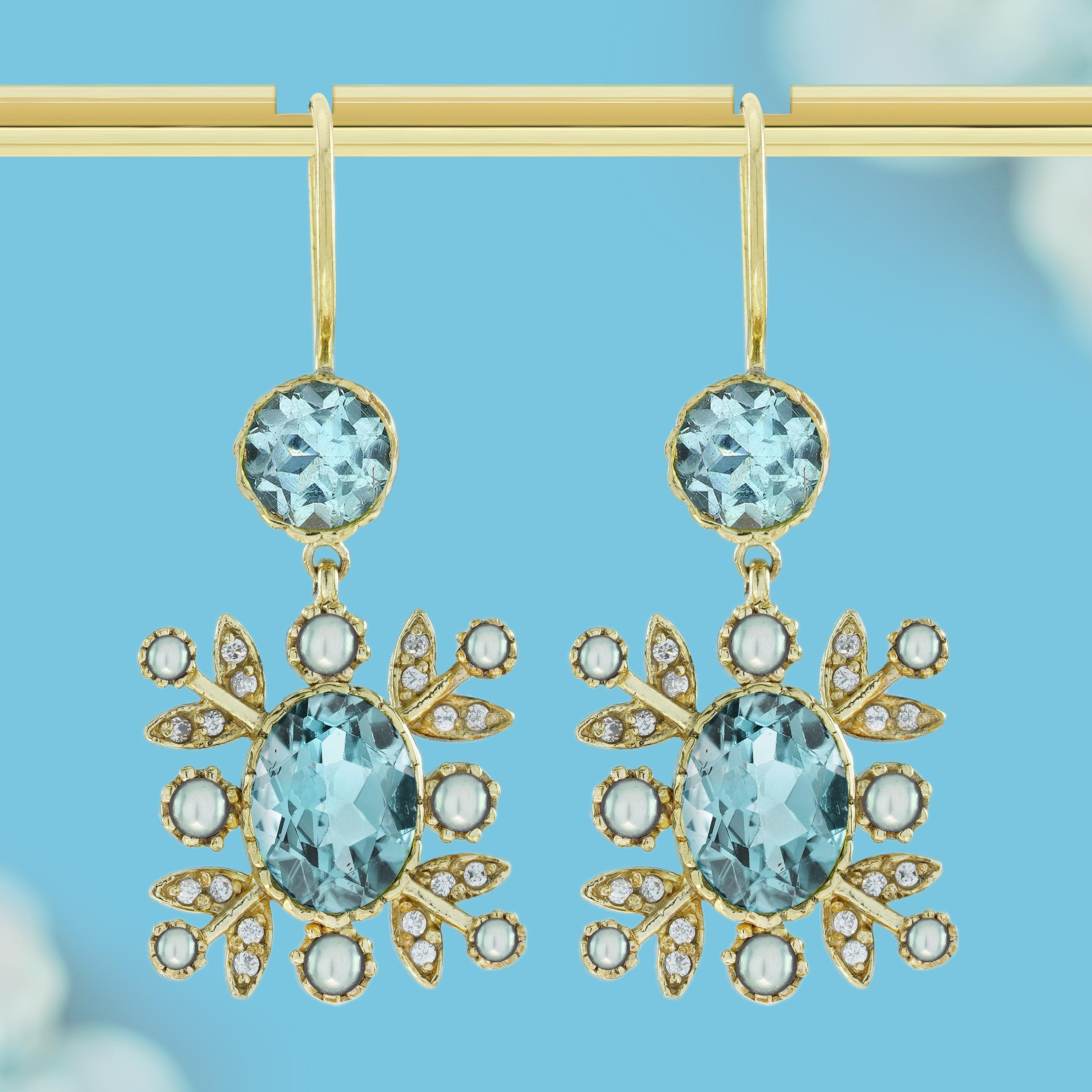 Diese floralen Tropfenohrringe mit natürlichem Blautopas und Perle im Vintage-Stil haben einen leuchtenden Blautopas in der Mitte, der die Staubgefäße einer blühenden Blume symbolisiert. Der Topas ist von zarten Perlenblättern umgeben, die einen