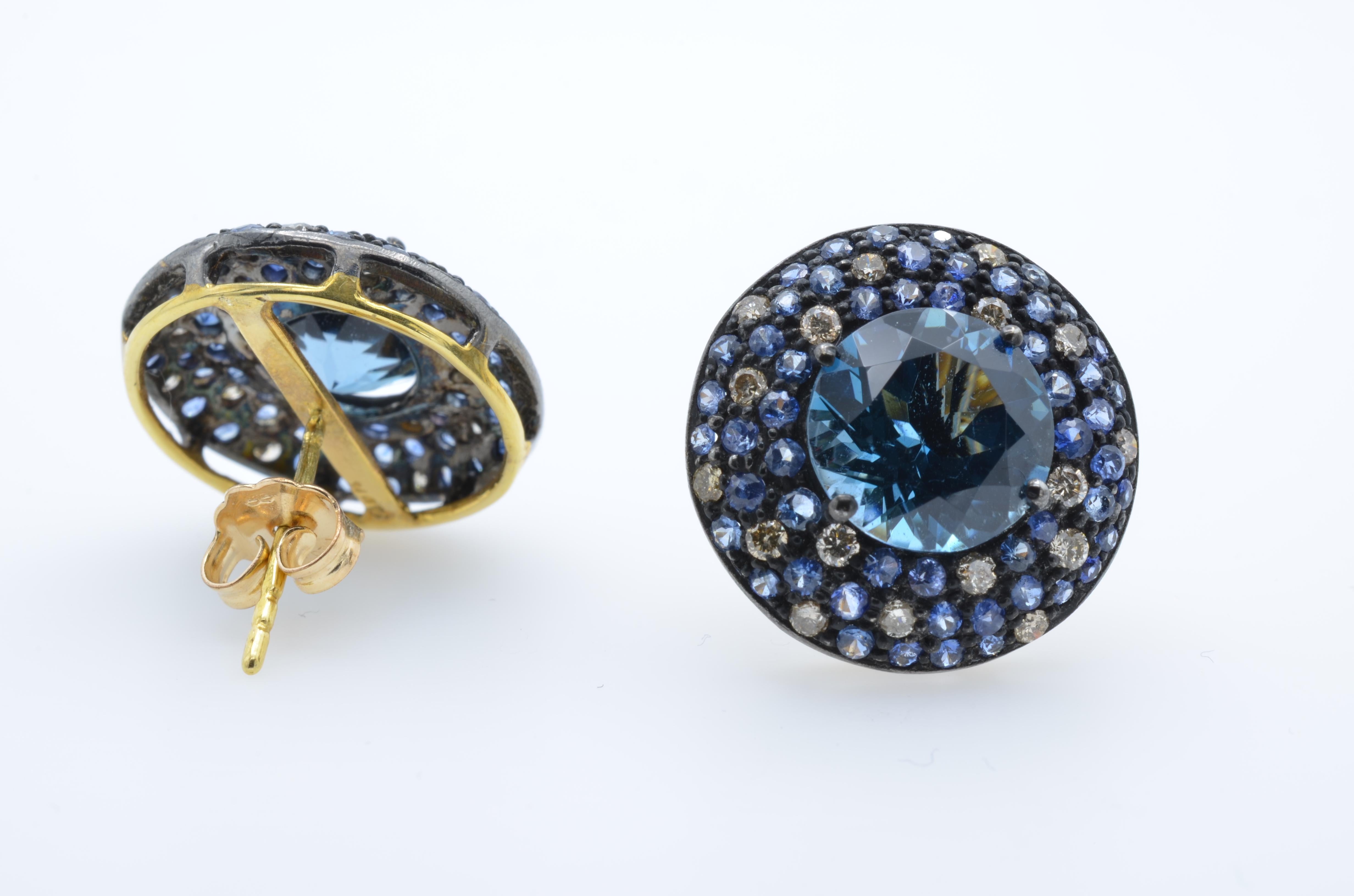This blue kaleidoscope of jewels surrounds a deep blue topaz. The diamonds and sapphires accent the topaz in a random pattern set in oxidized sterling silver and backed in 14k gold. They are fun and fanciful and full of dazzle!!