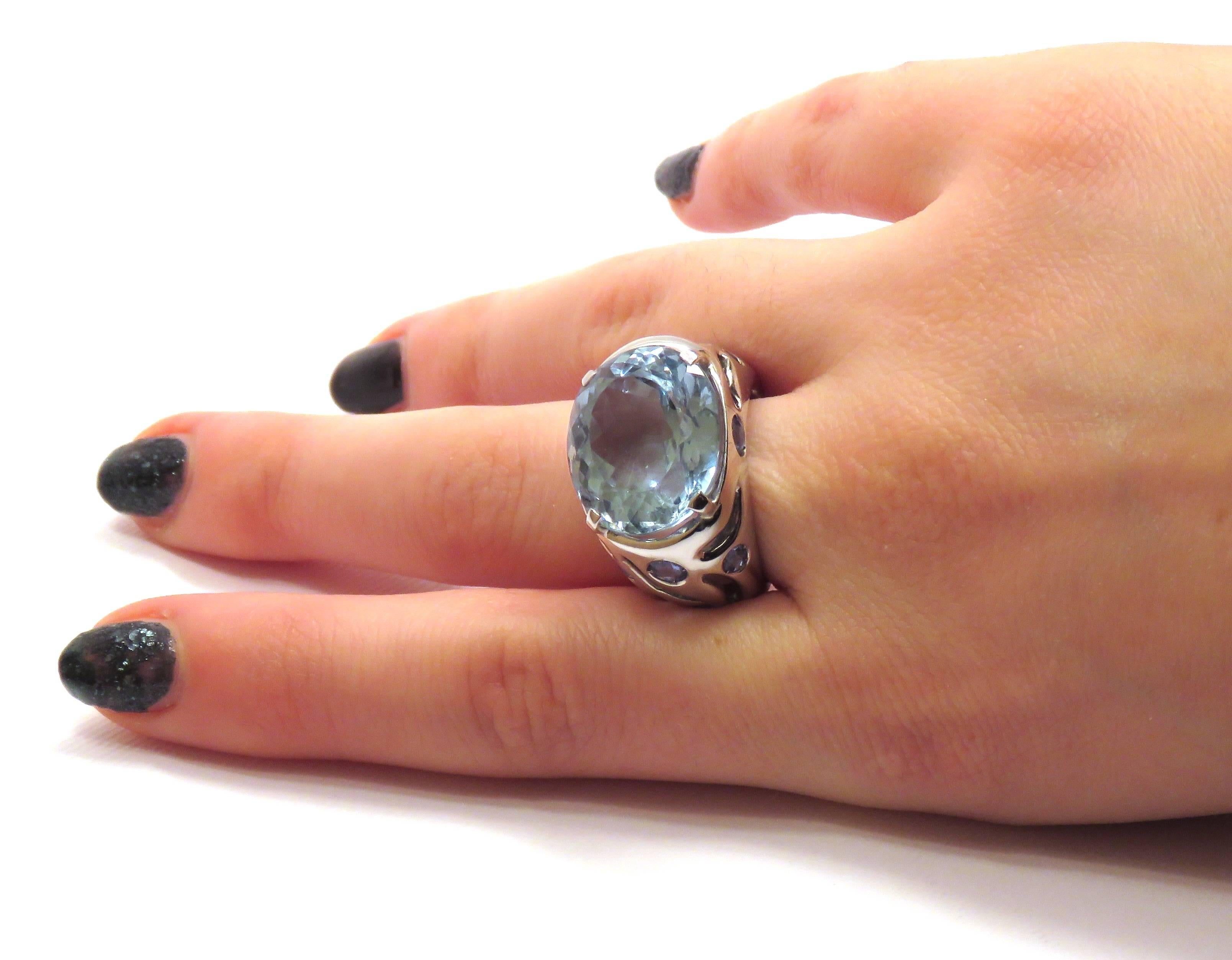 Stunning cocktail band ring handmade in 18k white gold featuring a large natural faceted blue topaz ctw 23.49. The band is decorated with carved waves and 10 blue sapphires ctw 3.40 totally.   
Us finger size 6 3/4, resizable. Marked with the