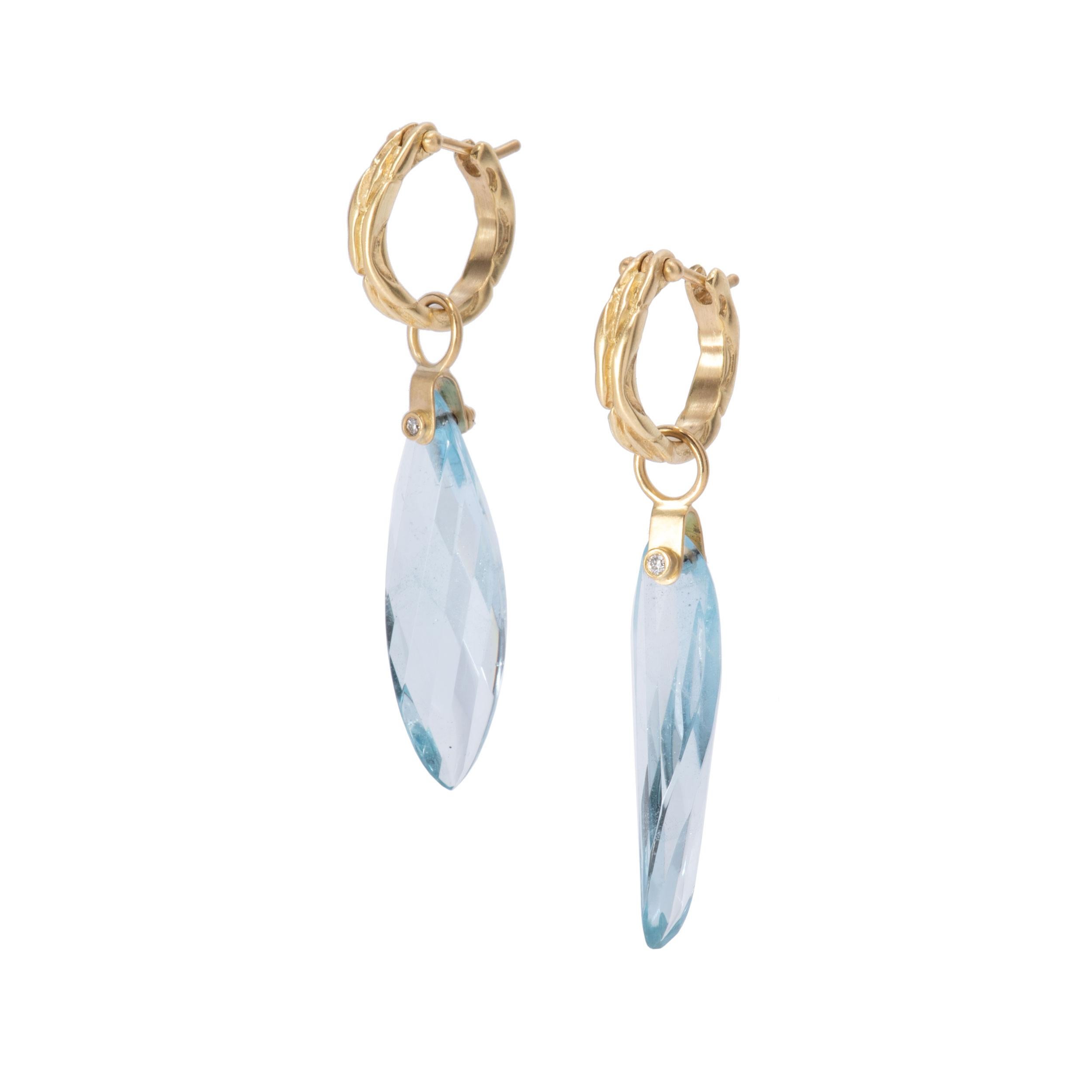 Blue Topaz Twisted Petal Drop Earrings in 18k gold are punctuated with .04ctw diamonds on stirrup mounts. Facets reflect twinkle and shadows in these blue topaz drops and the curved or twisted cut enhances the catch of light. Blue topaz petal drops