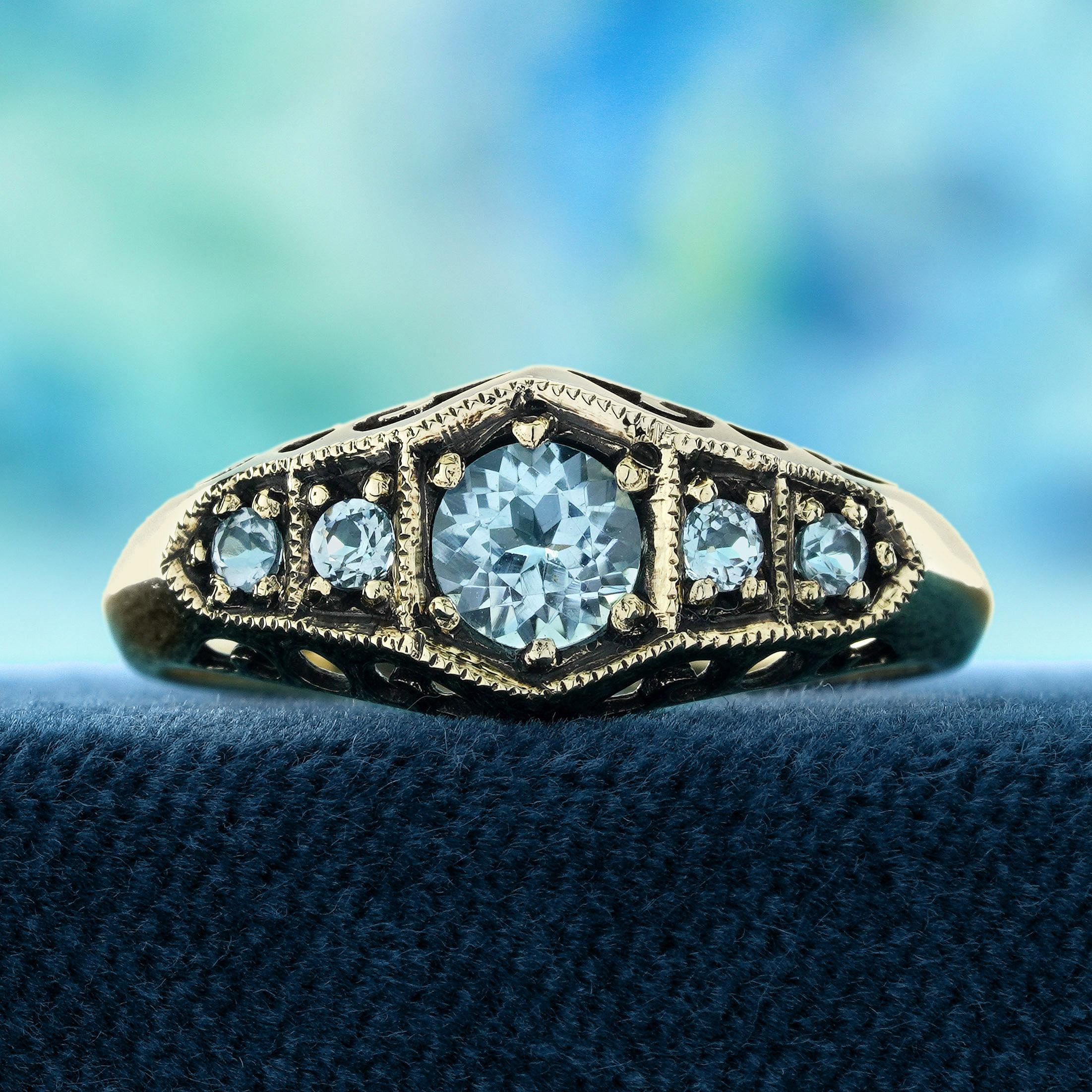 Un arrangement étonnant de cinq pierres de topaze bleue vibrantes, chacune soigneusement sertie dans un anneau complexe de style vintage. Les riches teintes bleues de la topaze créent un beau contraste avec la monture élégante et détaillée, offrant
