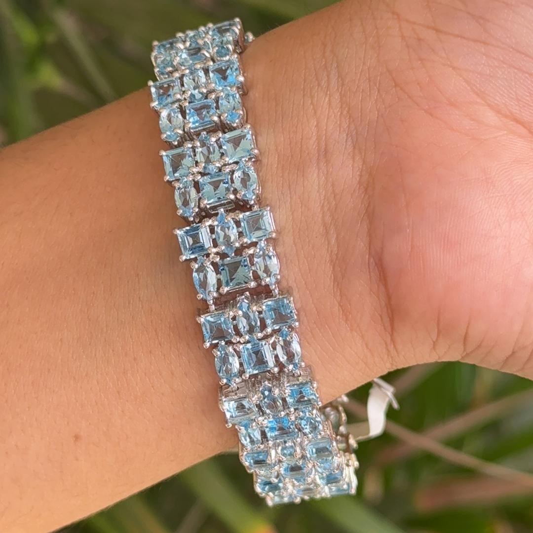 Blue Topaz Wide Cocktail Tennis Bracelet in sterling silver showcases endlessly sparkling natural blue topaz, weighing 27.2 carat. It measures 7 inches long in length.
Natural Blue Topaz stimulate concentration and reduces stress.
Designed with