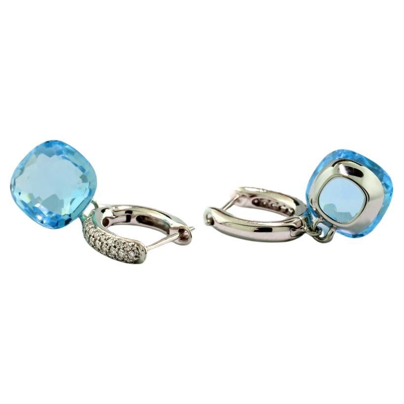 A pair of eye-catching earrings featuring two  Blue Topaz gemstones approx. 11.58 carats in total. The topazes, displaying a vibrant Swiss Blue color with fine luminosity, are cushion-cut, elegantly showcased in smooth linear settings. Suspended