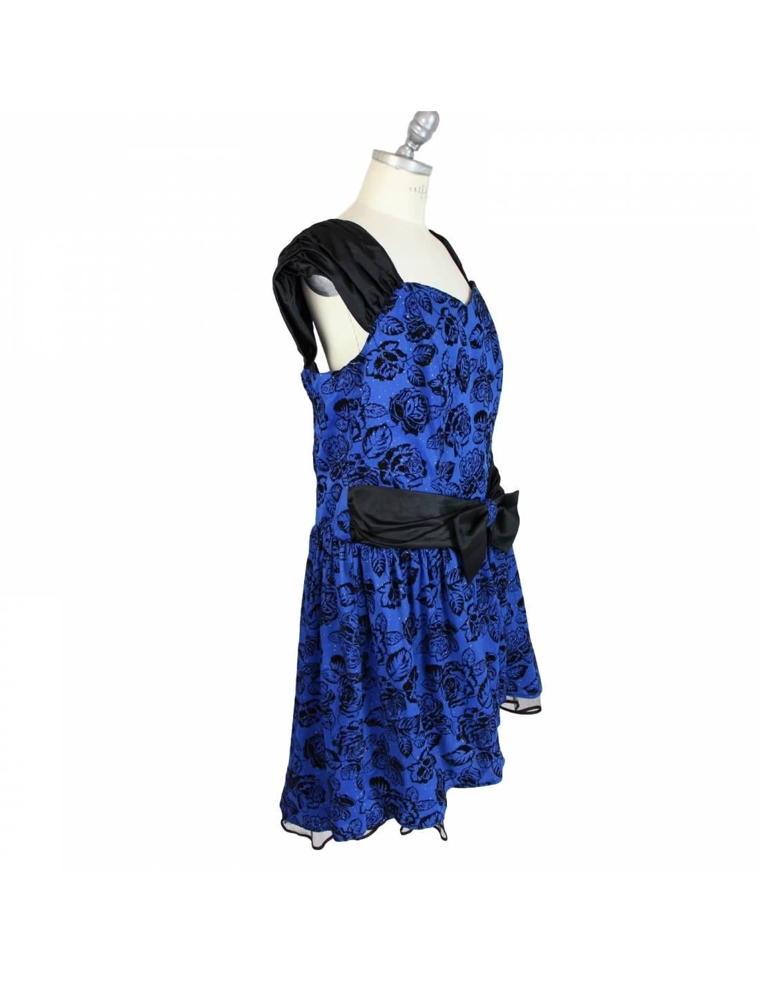 Oversized vintage sartoriale dress 80s rockabilly style, color blue background designs. Cocktail party dress. Short sleeves, floral designs and black bow at the waist. The balloon skirt is made of tulle and is longer behind.

Made in Italy.