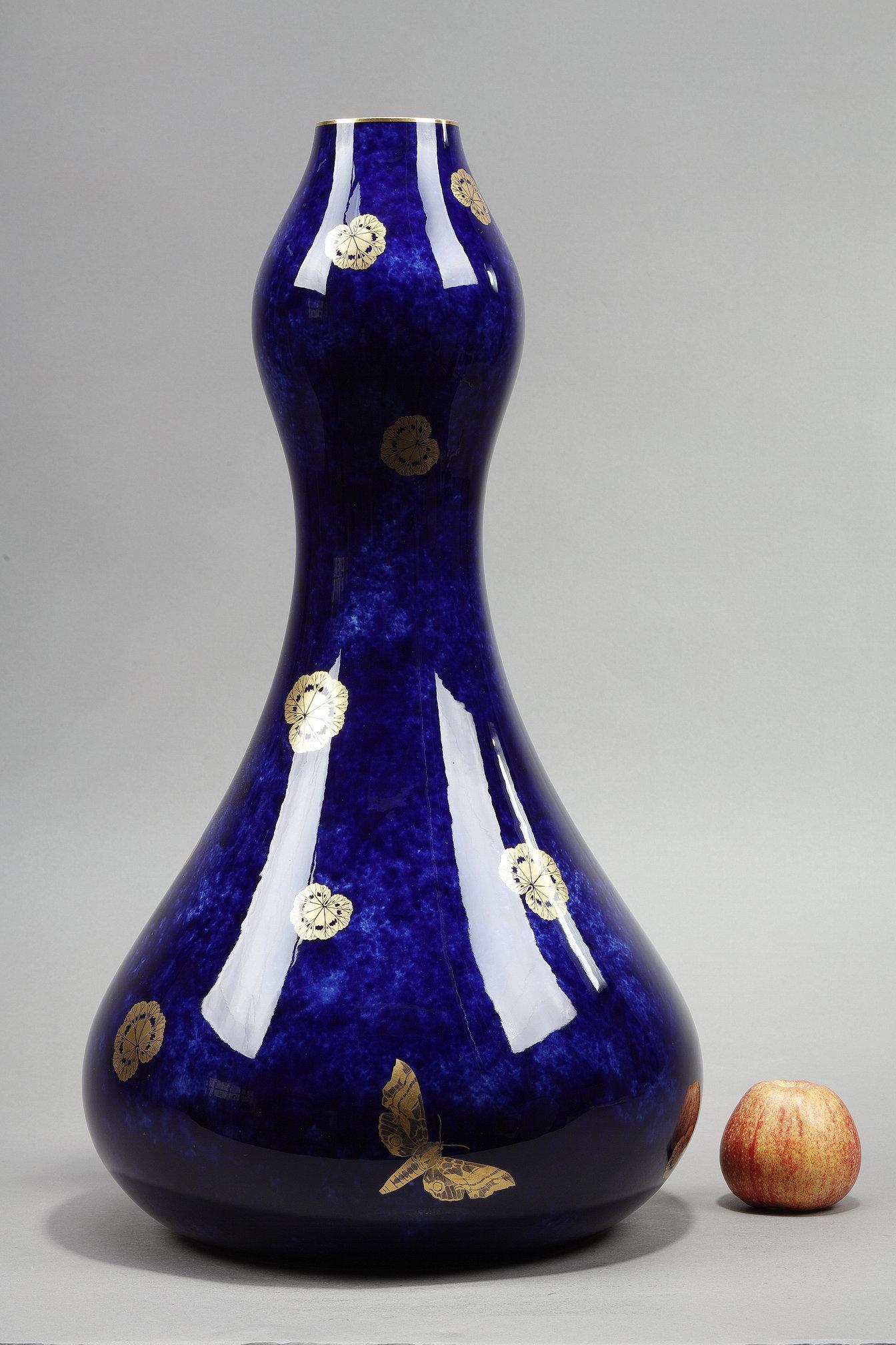 Vaso coloquinte molto grande della Manufacture Nationale de Sèvres. Porcellana dura con decorazione dorata di foglie di ninfea e farfalle su un fondo blu notte sfumato. Collo e tallone evidenziati da un bordo listellato dorato. Timbro triangolare