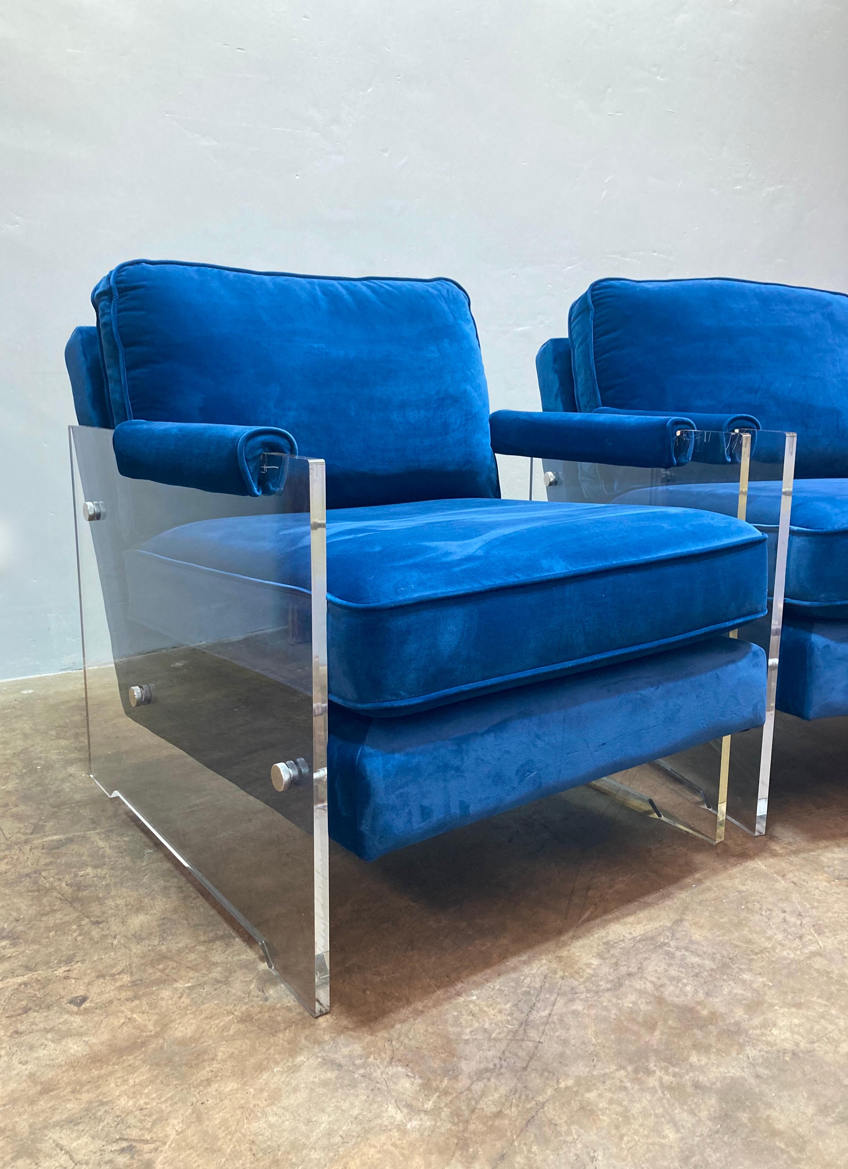 Beautiful pair of armchairs are constructed with translucent acrylic frames, and upholstered in deep turquoise velvet. The practical design is comfortable for lounging, while being a striking design element in any room. Chairs are in excellent